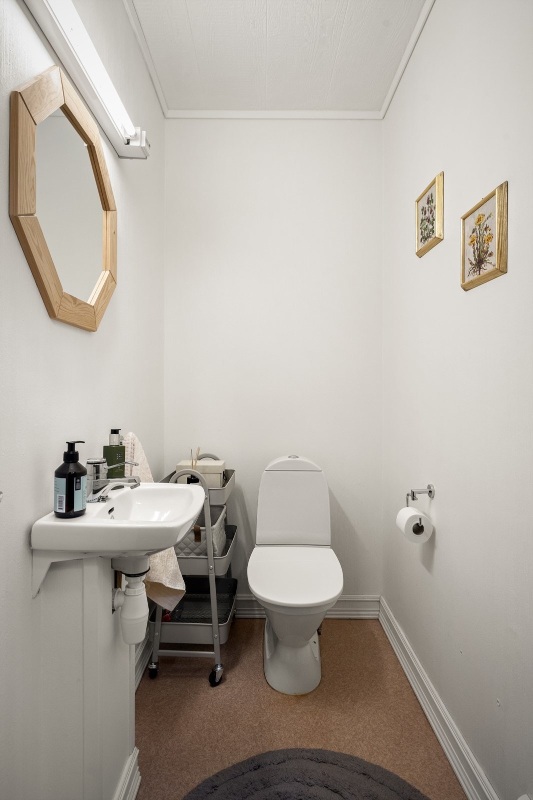 Toalettrom i u.etasje med belegg på gulvet og malt strie på vegger.
Rommet er innredet med enkel servant samt toalett. Ventilasjon via ventil tilkoblet mekanisk avtrekk. Galleribilde