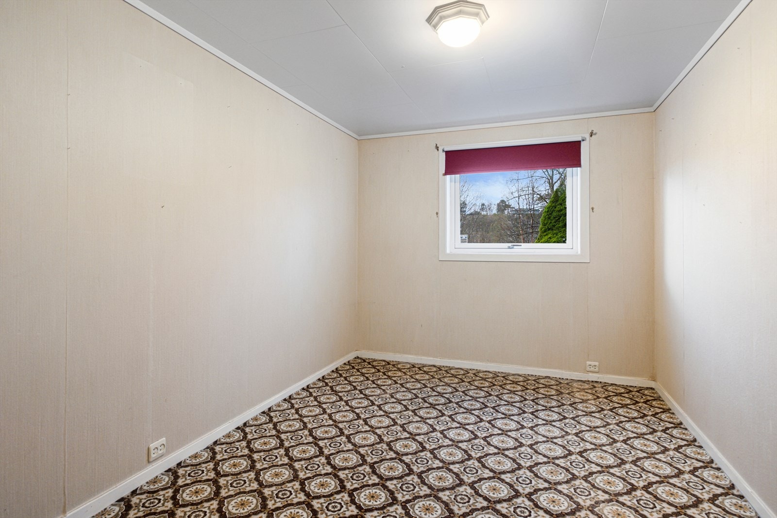 Rommet har tapetserte vegger og belegg på gulv, med vindu som gir lysinnslipp. Galleribilde