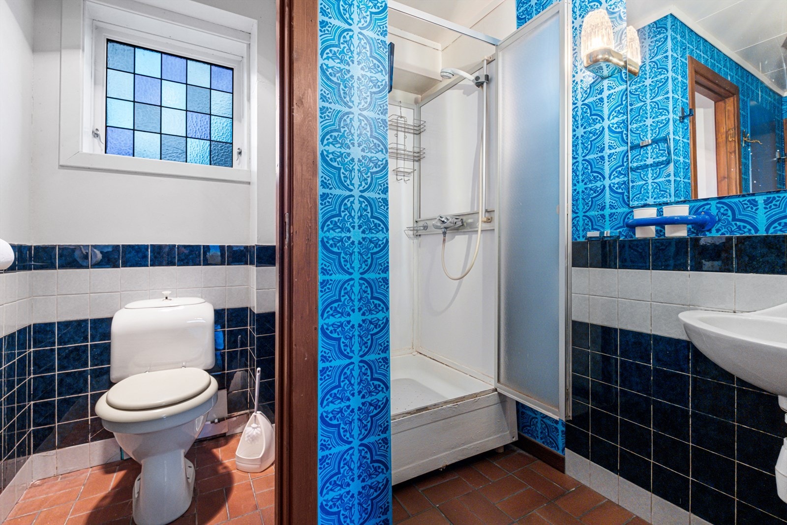 Badet har fliser på gulv og vegger, med dusjkabinett og toalett. Galleribilde