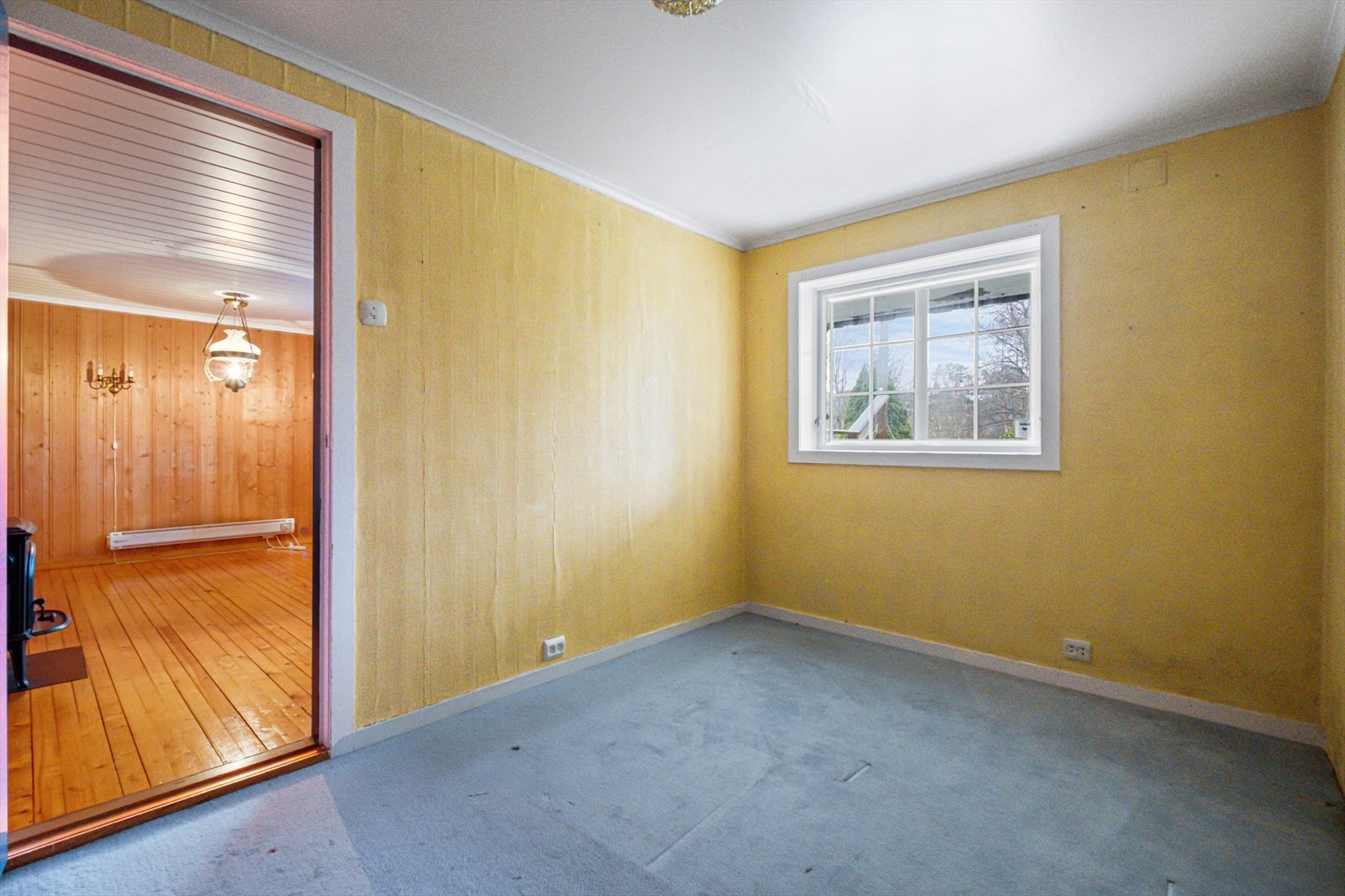 Rommet har gulvteppe og tapet på veggene, med vindu som gir naturlig lys. Galleribilde