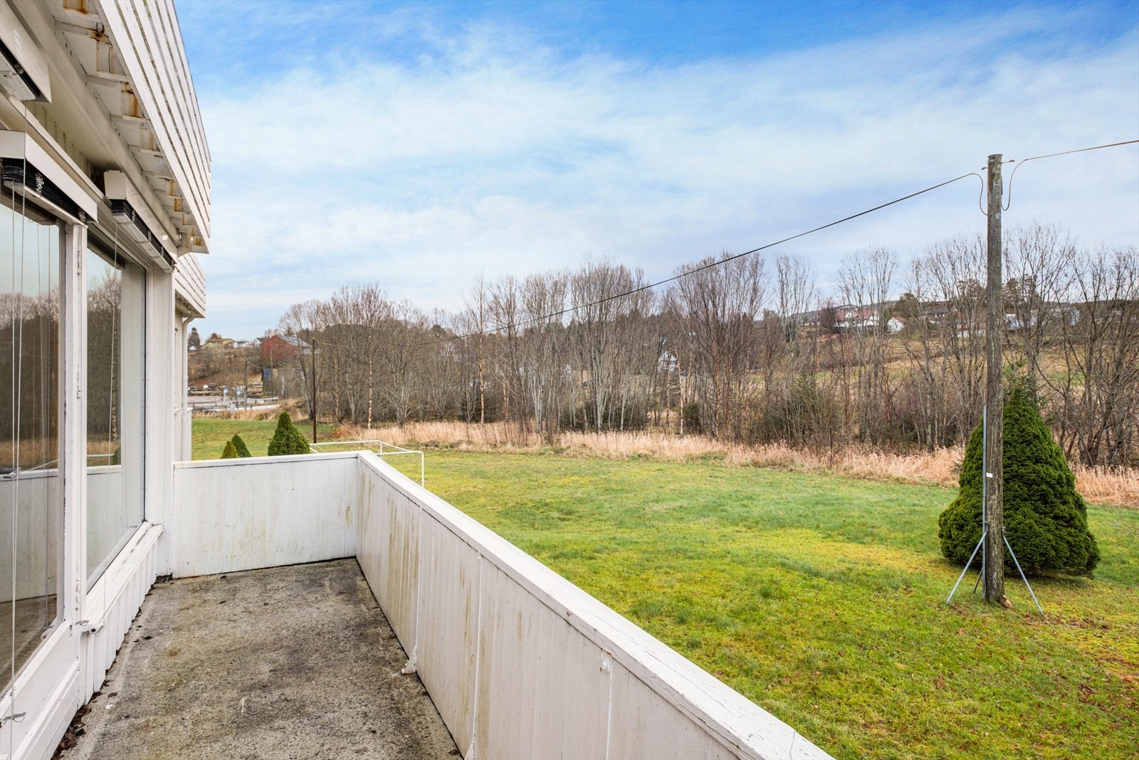 Verandaen har betonggulv og gir utsikt mot grøntområde og nabolag. Galleribilde