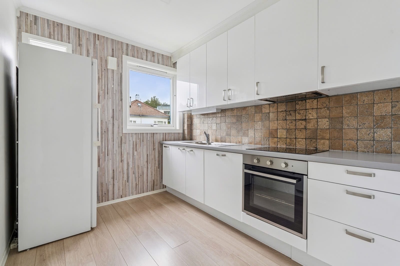 Moderne kjøkken med hvite fronter, god benkeplass og naturlig lys. Galleribilde