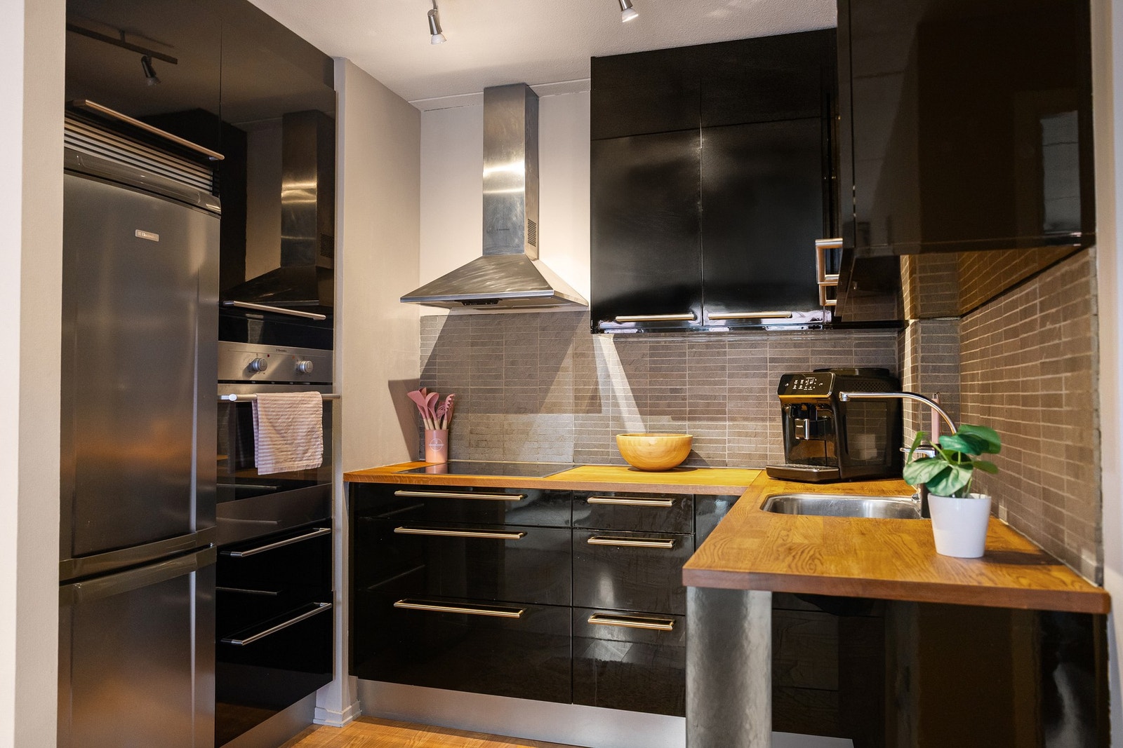 Videre er kjøkkenet utstyrt med nedfelt keramisk platetopp, komfyr plassert i høyskap, oppvaskmaskin under benk og frittstående kjøleskap med frysedel. Galleribilde