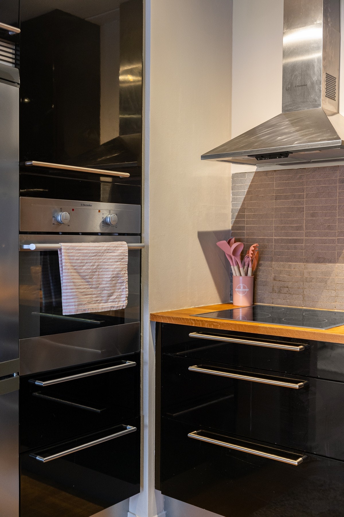 Det er fliser mellom benk og overskap, samt veggmontert ventilator. Galleribilde