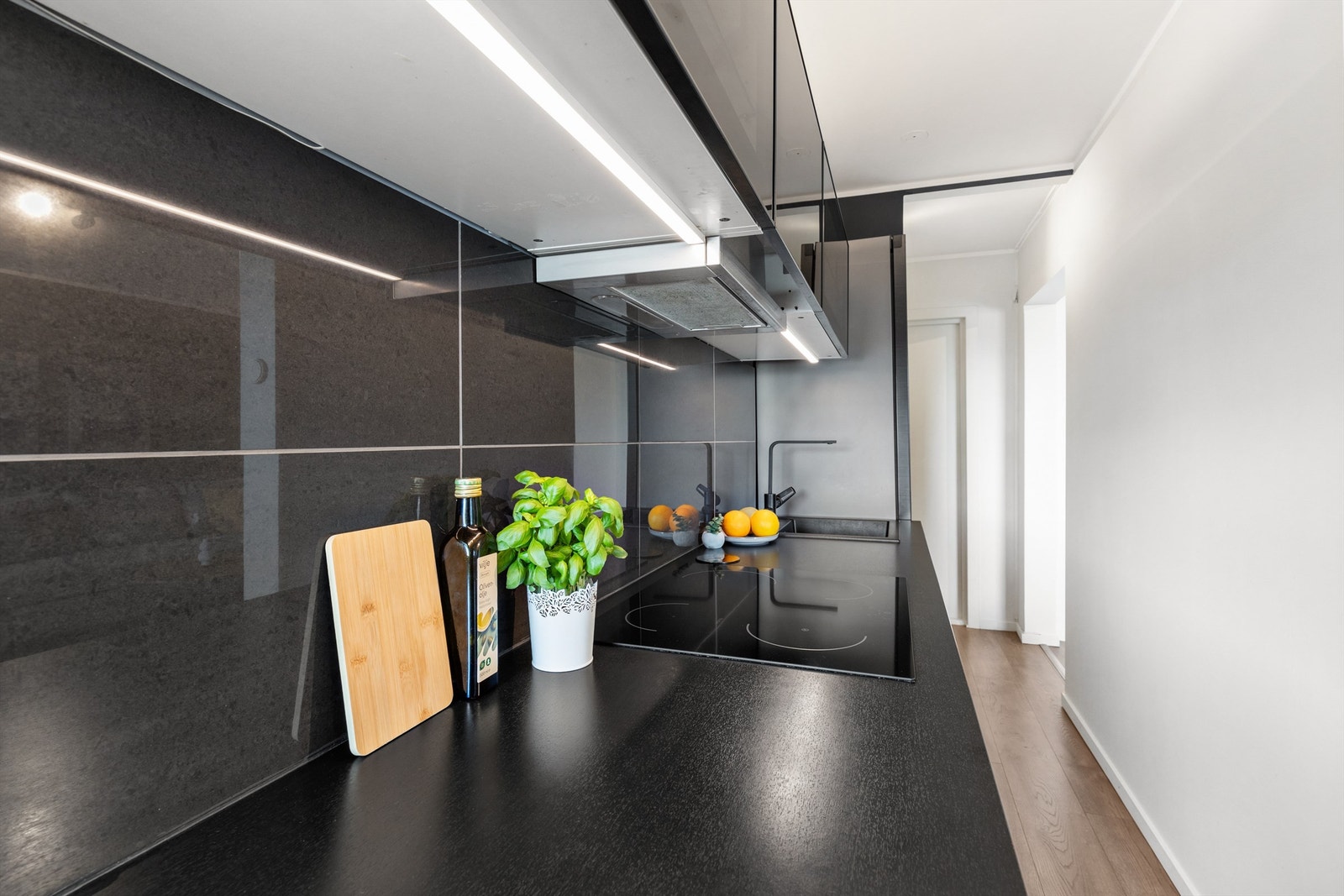 Kjøkkeninnredningen er lekker og består av profilerte fronter, laminat benkeplate med nedfelt oppvaskkum og fliser på vegg mellom kjøkkenbenk og overskap. Galleribilde