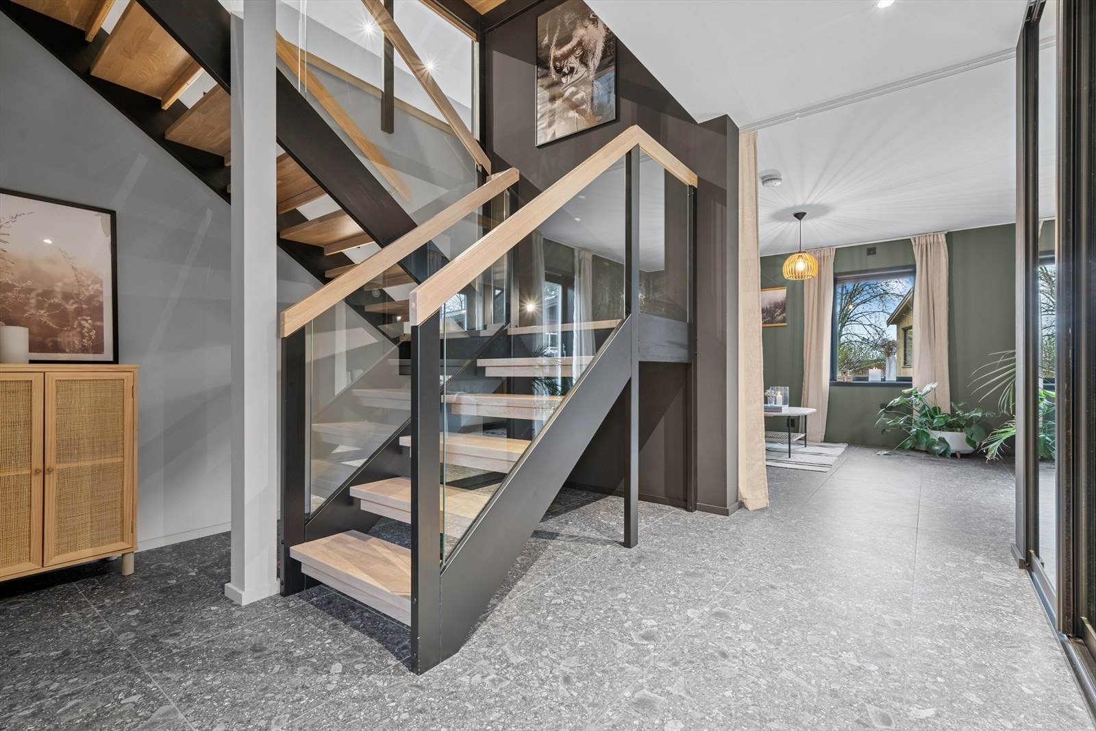 Stilig trapp i entrè med god plass til klær i skyvedørsgarderobe. Galleribilde