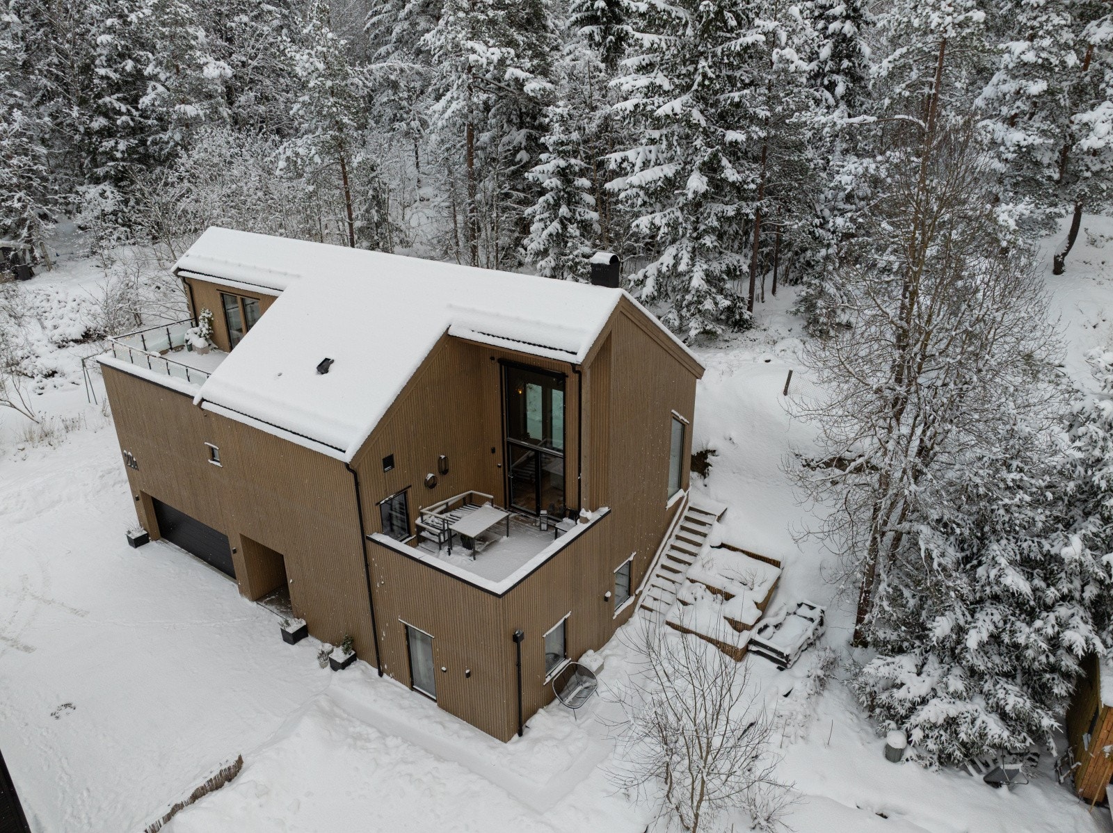 Boligen ligger med store vindusflater og uteplass mot skogen. Galleribilde