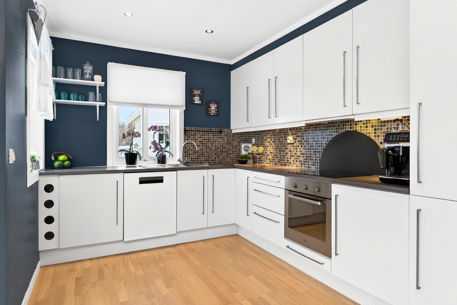 Et funksjonelt og godt utnyttet kjøkken med integrerte hvitevarer og slette fronter. Galleribilde