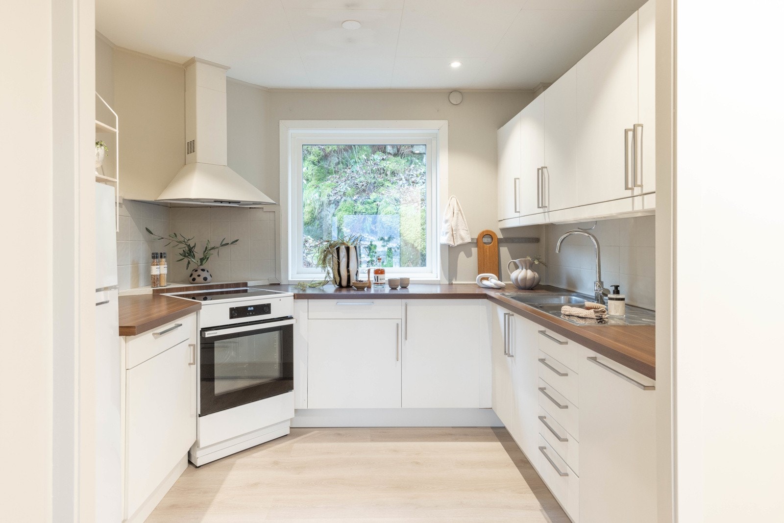 Det lyse, tidløse kjøkkenet fra Ikea har hvite, glatte fronter og en benkeplate i laminat. Galleribilde