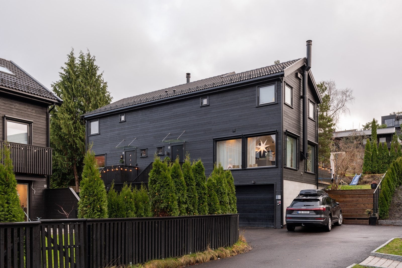 Beliggenhet tilbaketrukket fra vei med asfaltert innkjørsel og garasjeplass med lader og bod. Galleribilde