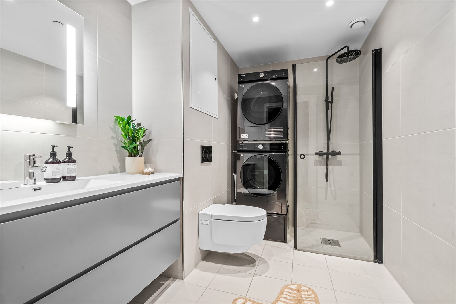 Delikat og innbydende bad med stor dusjsone, downlights, gulvvarme, servant med underskap og vegghengt dusjtoalett fra Geberit. Galleribilde