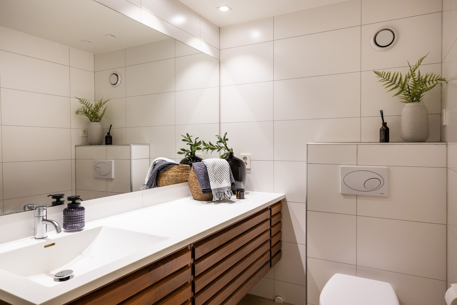 Pent flislagt bad med servant integrert i benkeplate med ett greps blandebatteri. Galleribilde