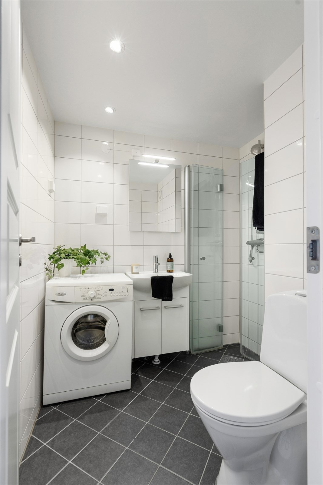 Badet har flislagte gulv med varmekabler, downlights i taket og moderne innredning med servantskap, speilskap med integrert belysning og dusjhjørne med innfellbare glassdører. Galleribilde