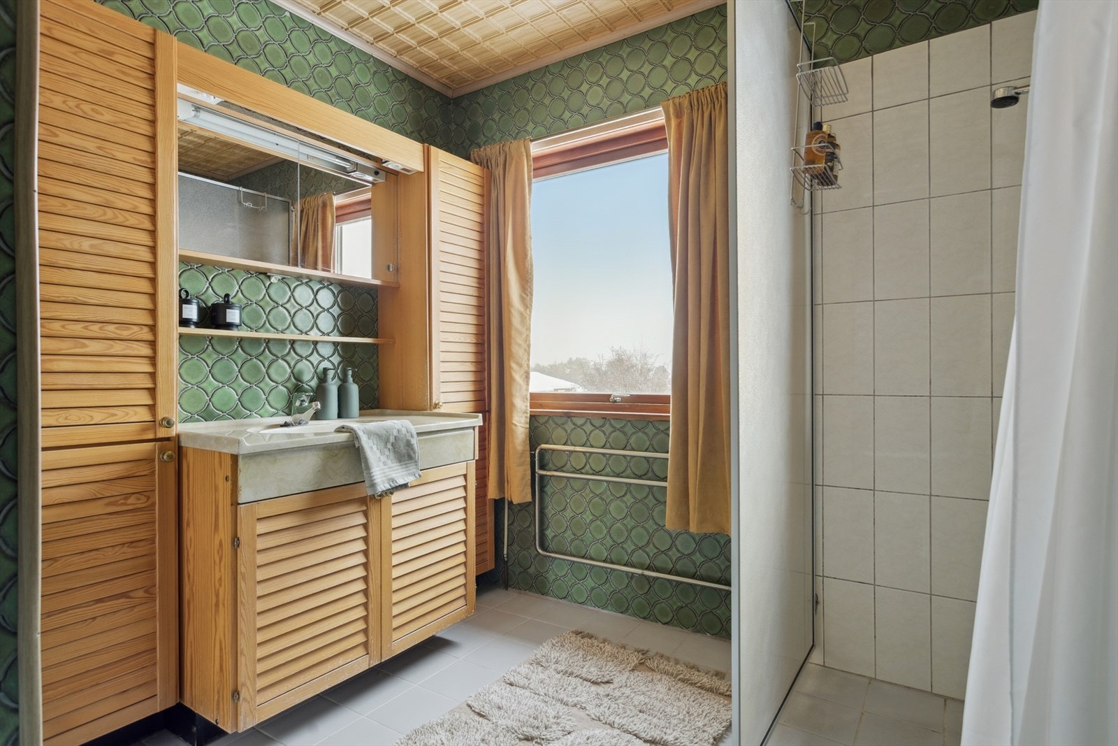 I tillegg finnes en dusjnisje med dusjvegg og forheng. Et stort vindu gir rikelig dagslys og en fin utsikt mot naturen, noe som skaper en lys og luftig atmosfære. Galleribilde