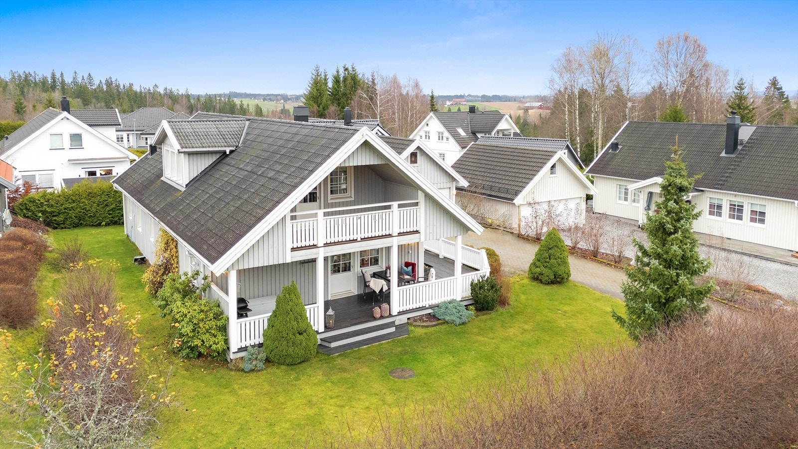 Boligen ligger på en flat og pent opparbeidet tomt med gressplen, terrasse og en innbydende innkjørsel med belegningsstein Galleribilde