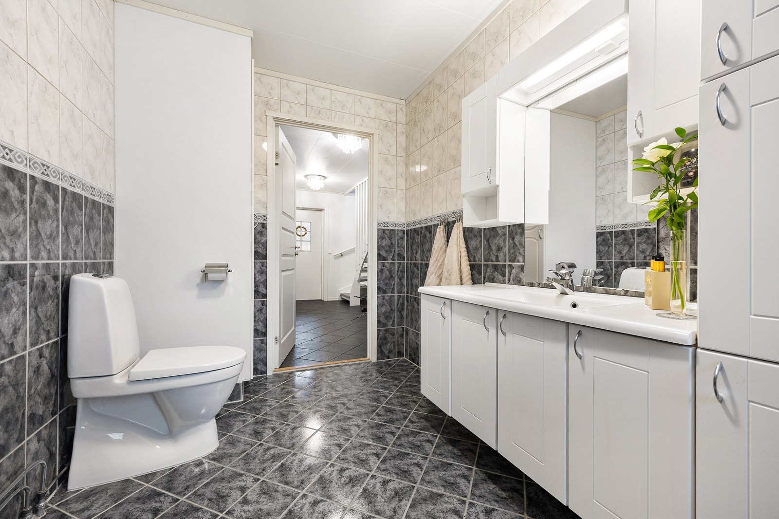 Baderomsinnredningen består av benkeskap, veggskap og høyskap med profilerte fronter, samt speil over servanten Galleribilde