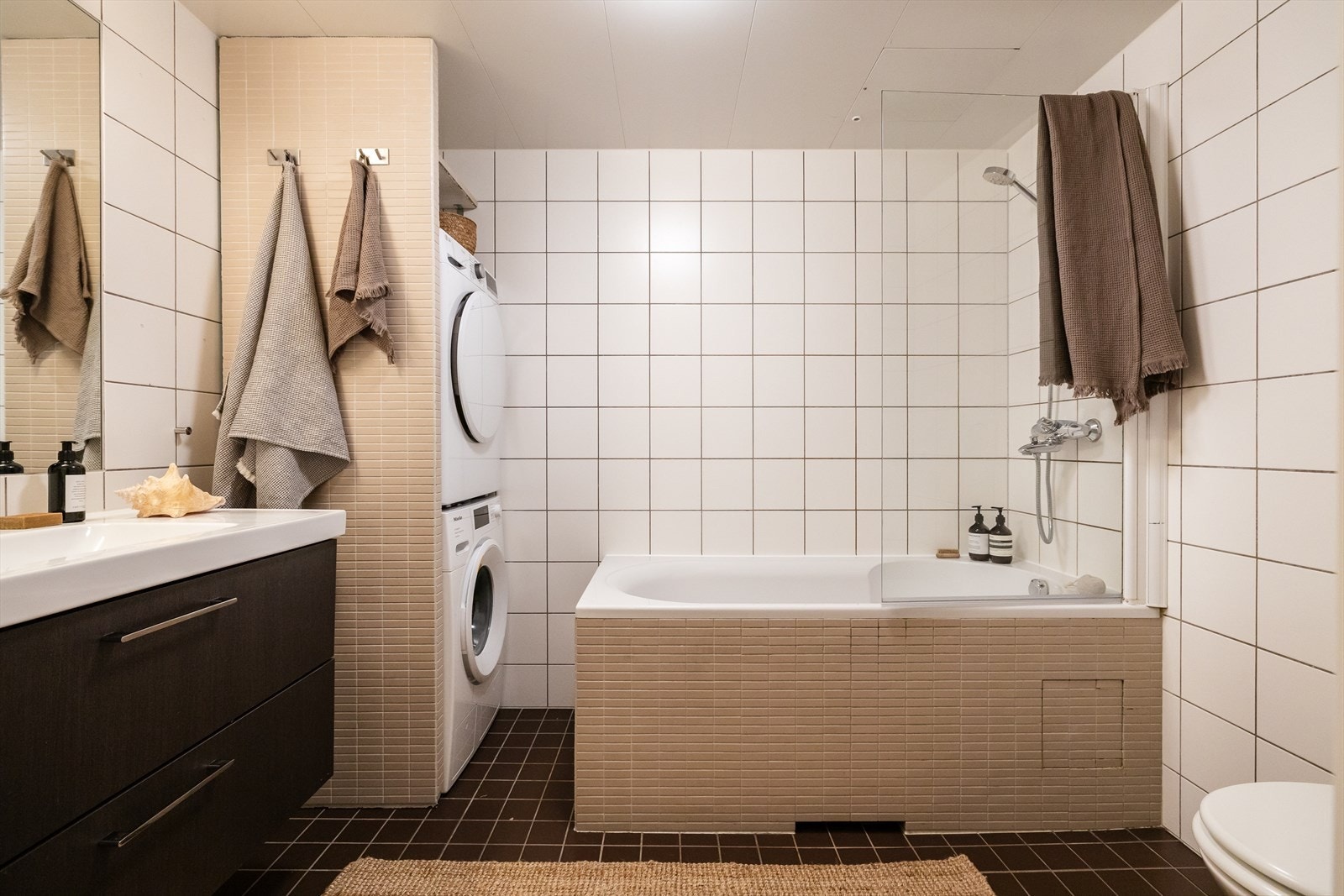 Romslig og pent baderom fra byggeår med innfliset badekar, heldekkende servant på underskap, speil og belysning. Galleribilde