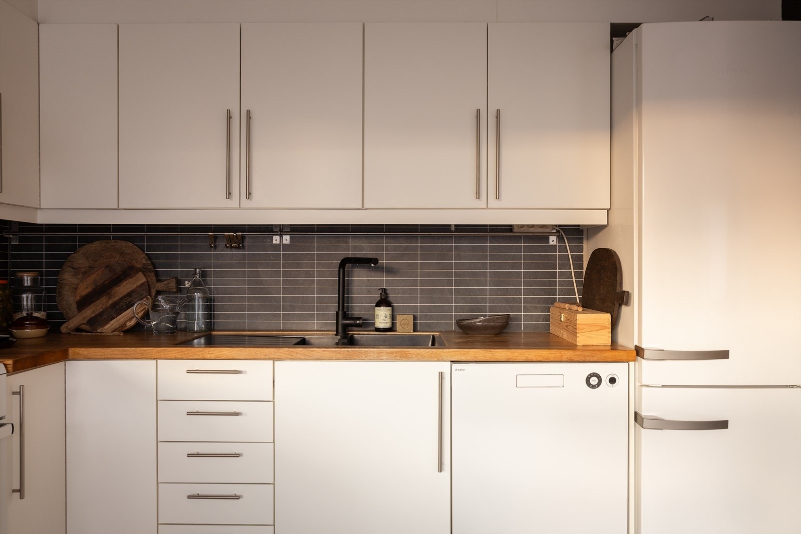 Kitchenboard mellom benk og overskap. Opplegg for vaskemaskin og mekanisk avtrekk fra ventilator. Galleribilde