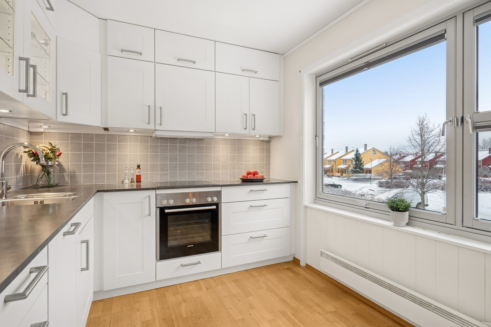 Kjøkkenet er innredet med folierte skrog med profilerte fronter og lagt flis. Flis på vegg over benkeplate. Galleribilde