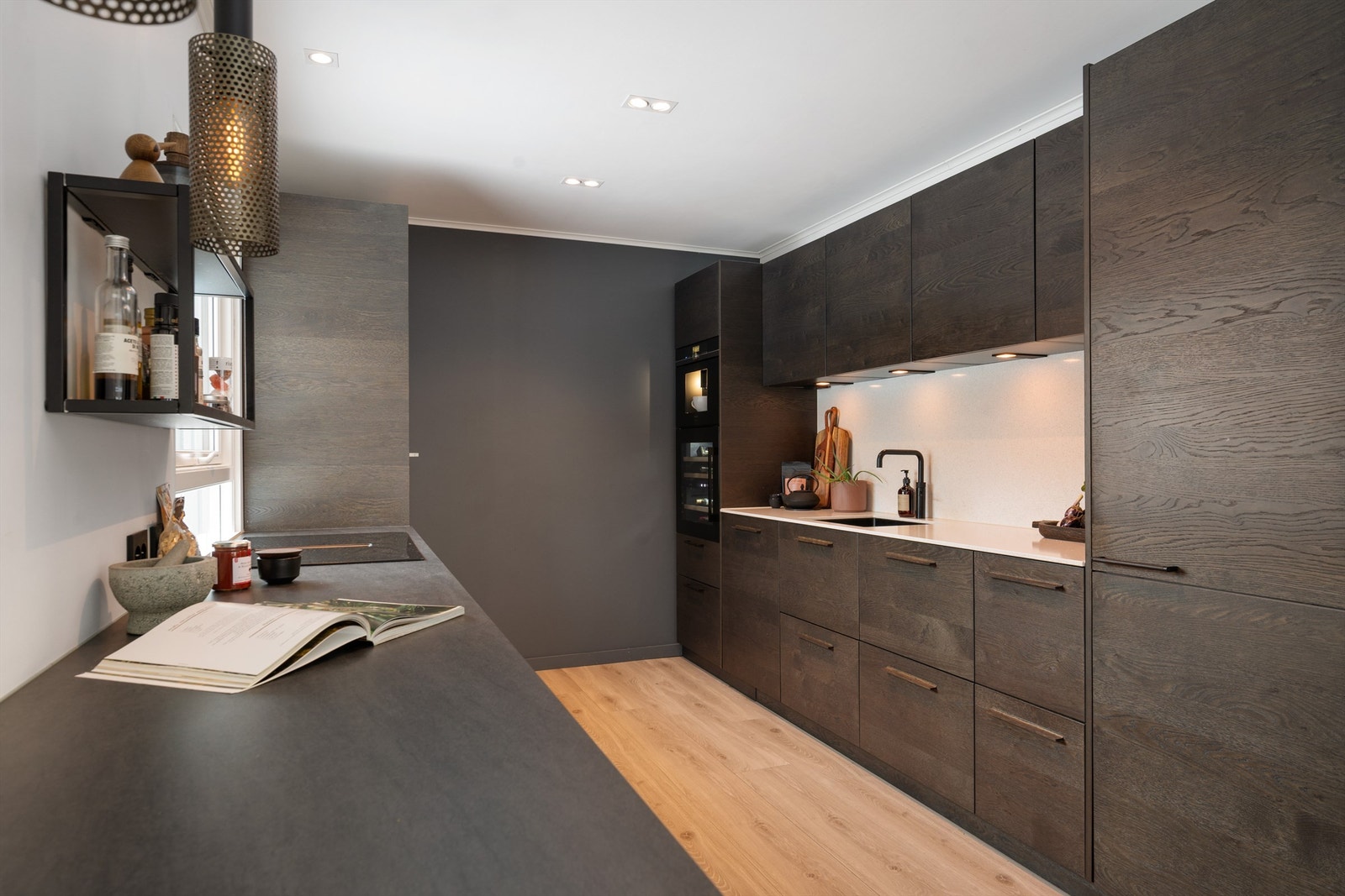 Kjøkkeninnredningen har integrerte hvitevarer og fronter i eikefiner og eikespiler. Benkeplater av keramikk og steinkompositt. Galleribilde