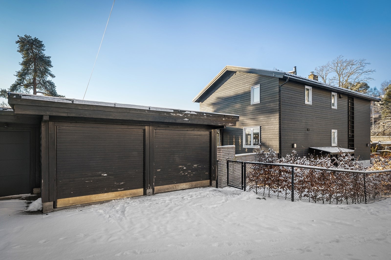 Kjedet dobbelgarasje som ligger usjenert til i tomtens ytterkant - Den brukes i dag primært til lagring og har 2 boder Galleribilde
