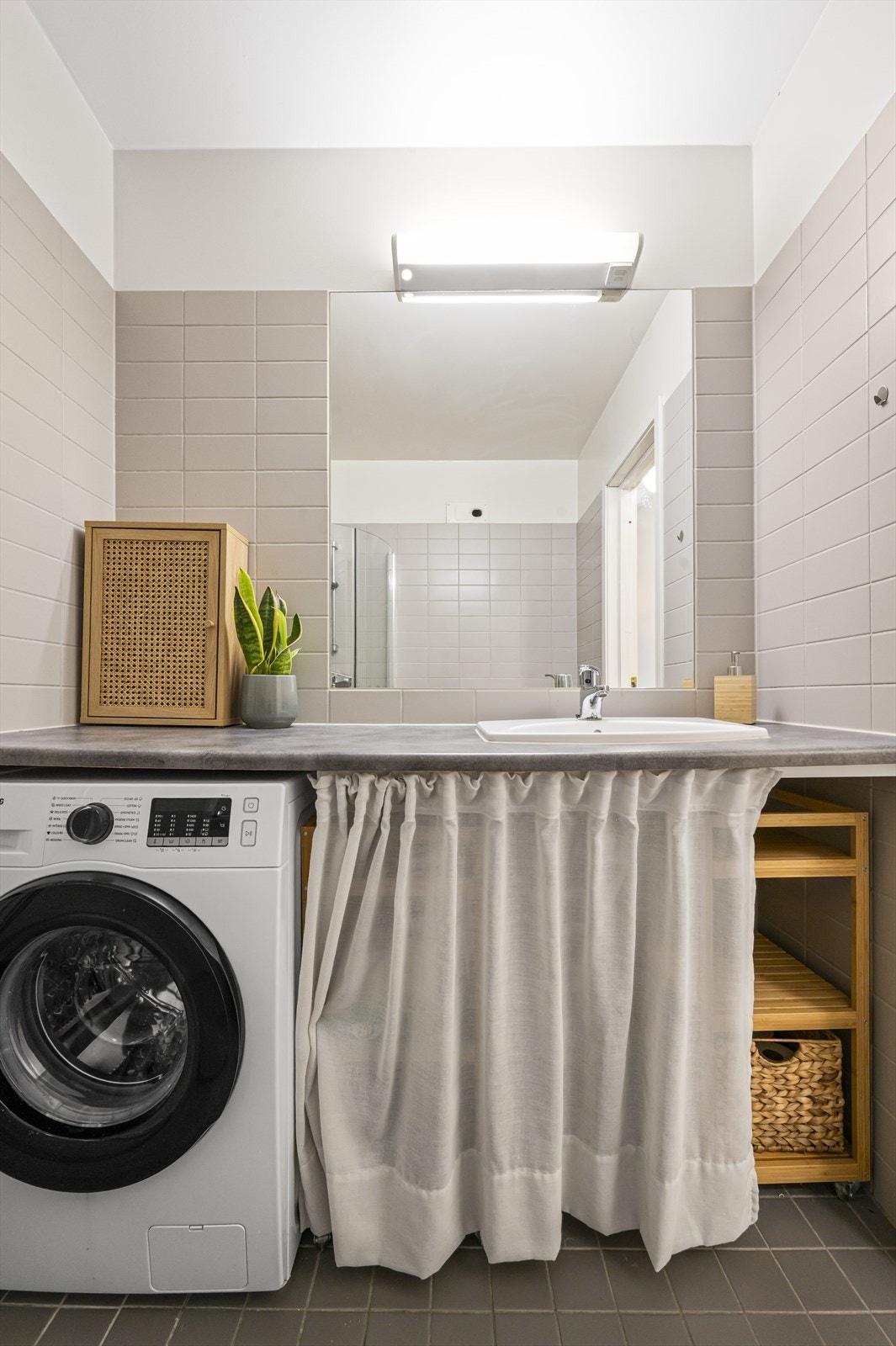 Innredningen består av fliser på gulv og vegger. Det er opplegg for vaskemaskin. Ellers er det gulvstående toalett, og benkeplate i laminat med nedfelt servant. Galleribilde