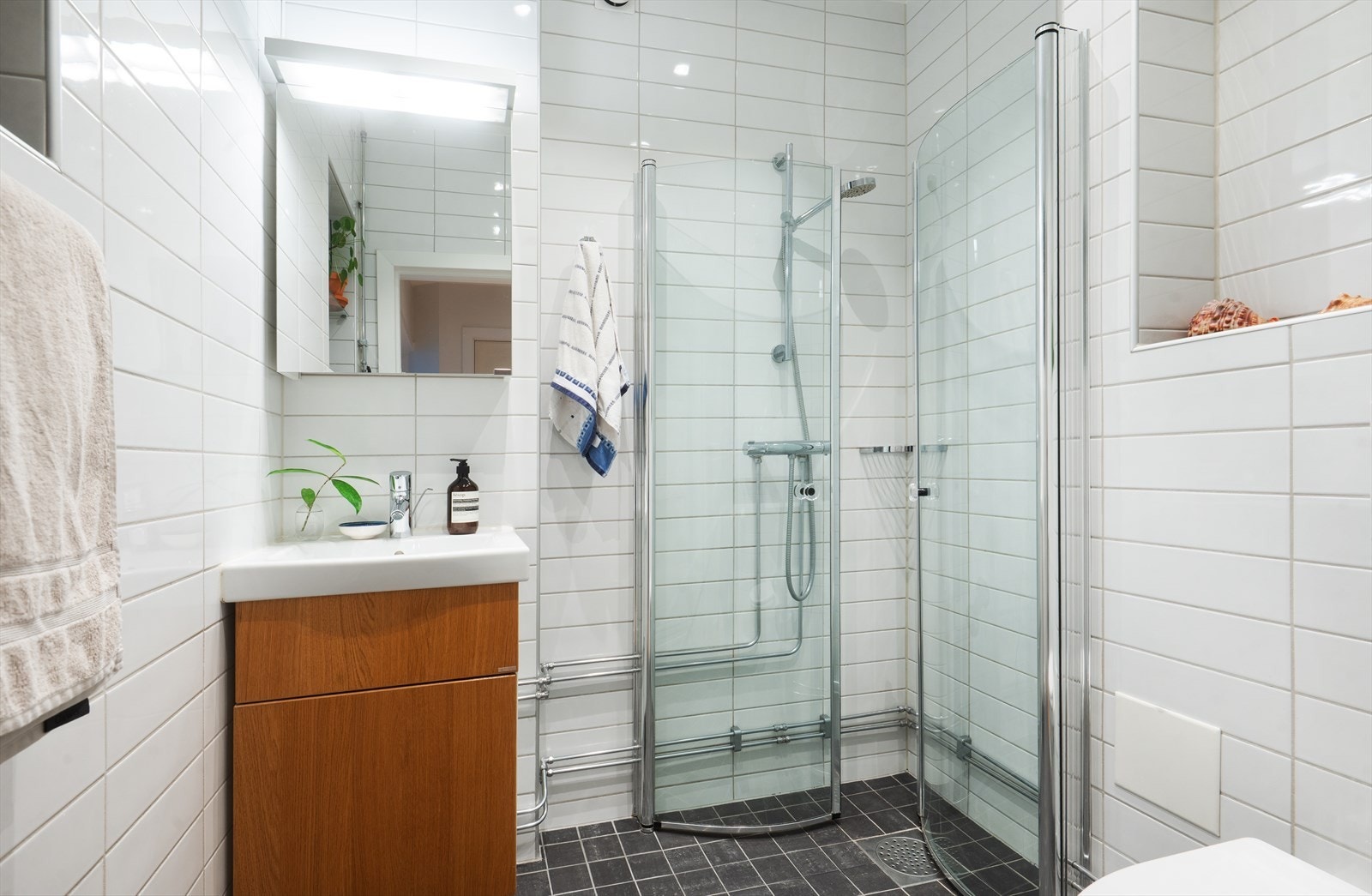 Baderom med mørke fliser på gulv med gulvvarme og lyse fliser på veggene Galleribilde