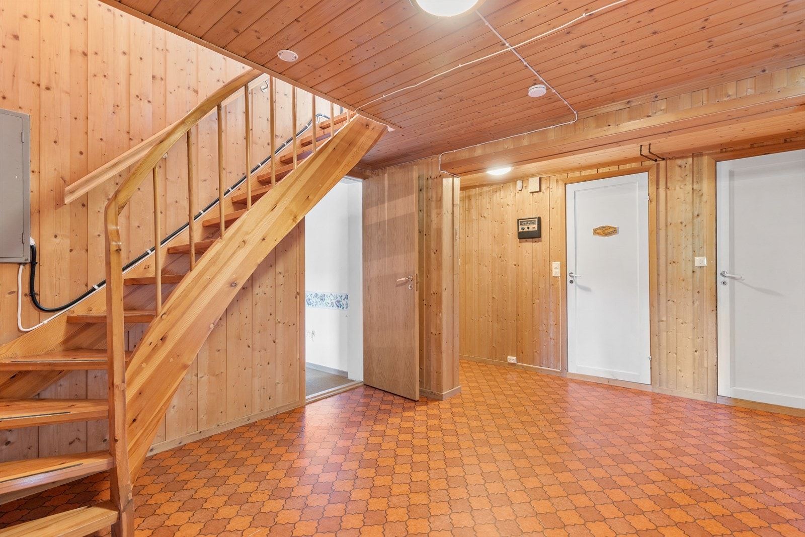 En solid tretrapp leder ned til underetasjen, som har en himlingshøyde på 2,20 meter i kjellerstuen. Galleribilde