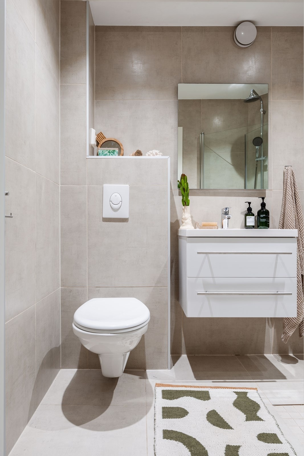 Praktisk baderom med servant, dusjhjørne og veggmontert toalett. Galleribilde