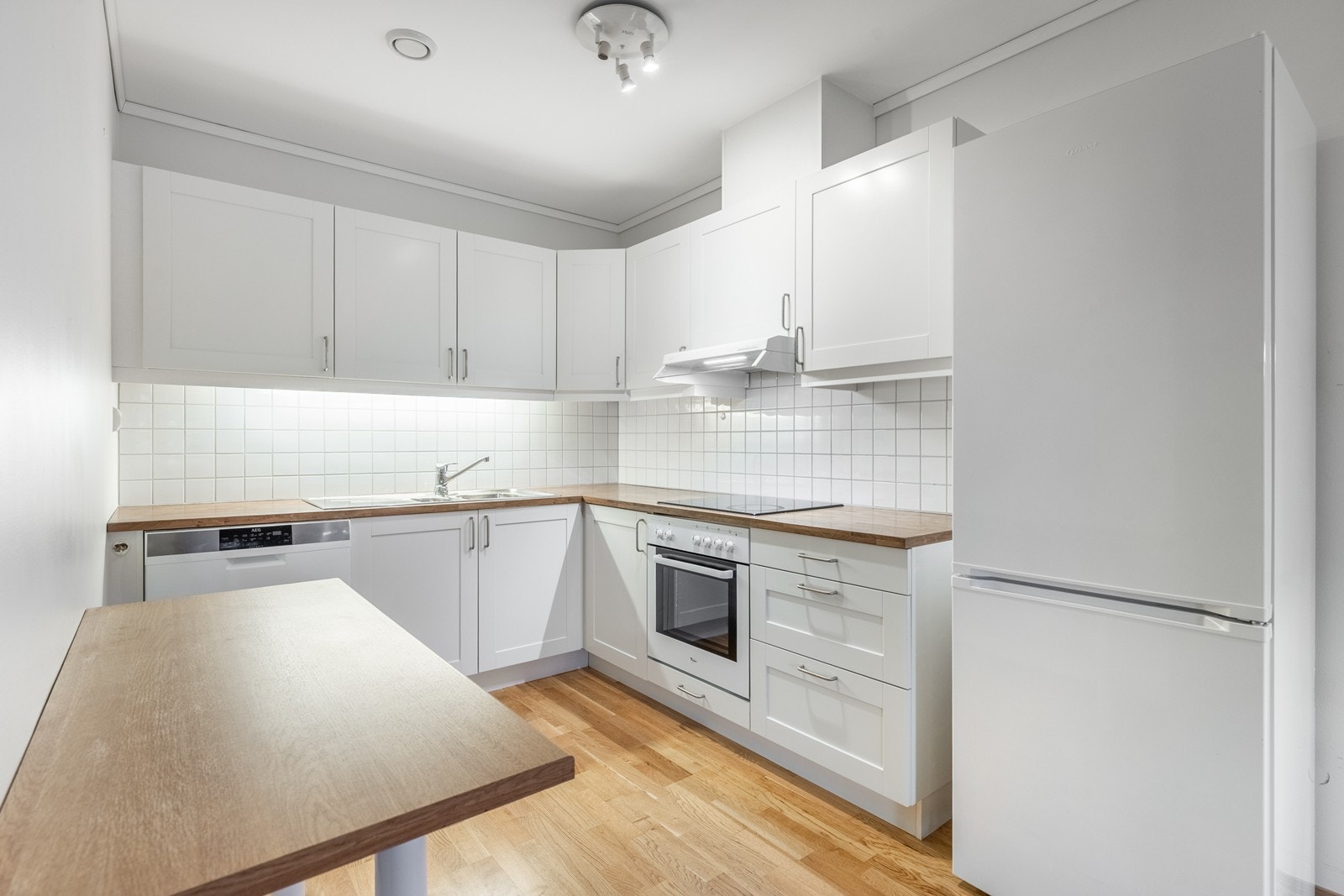 Kjøkkeninnredning er i hvit utførelse med medfølgende oppvaskmaskin, stekeovn, platetopp, ventilator og kjøleskap m/ frys Galleribilde