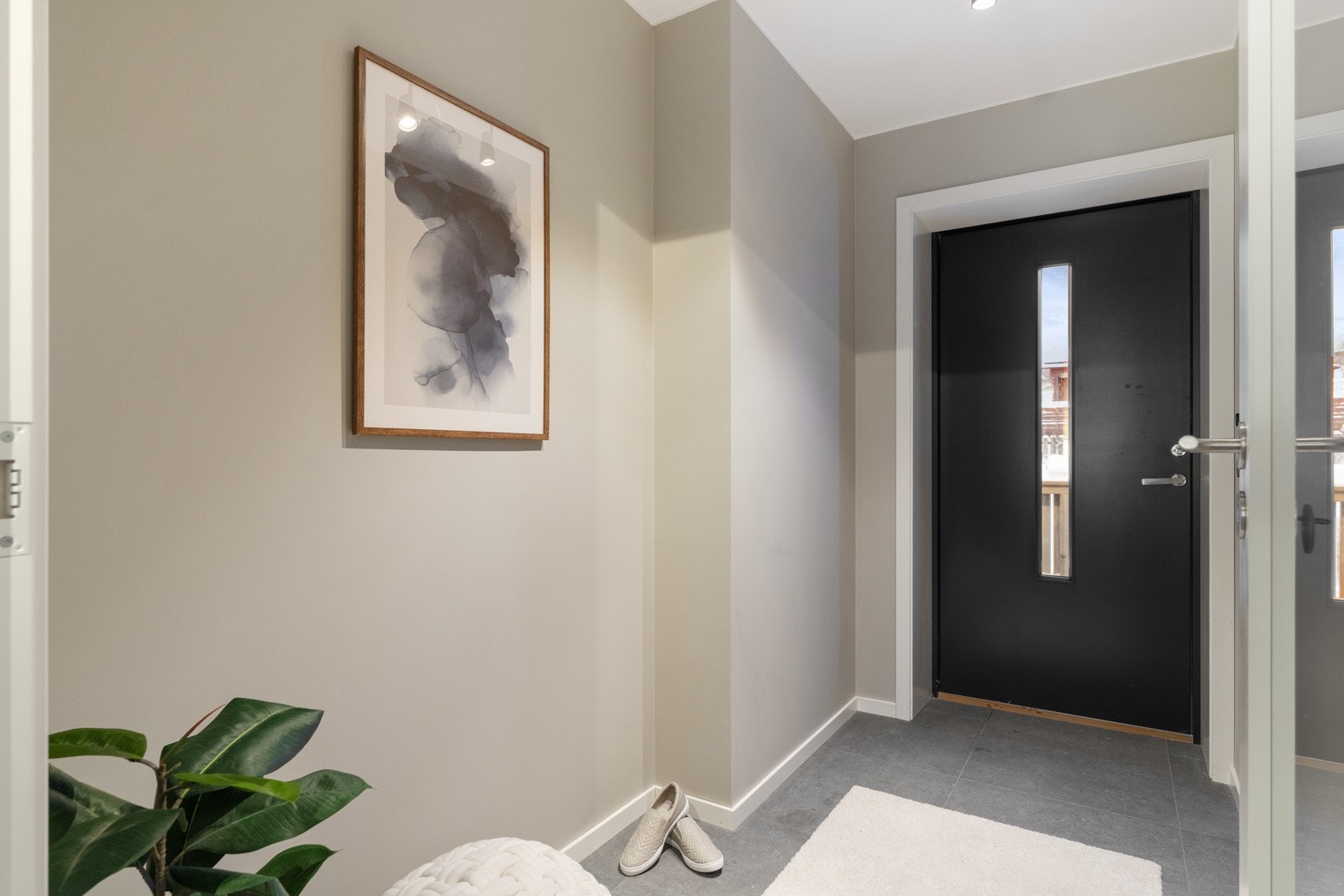 Boligen ønskes velkommen via en romslig entré med stilrene, grå fliser. Galleribilde
