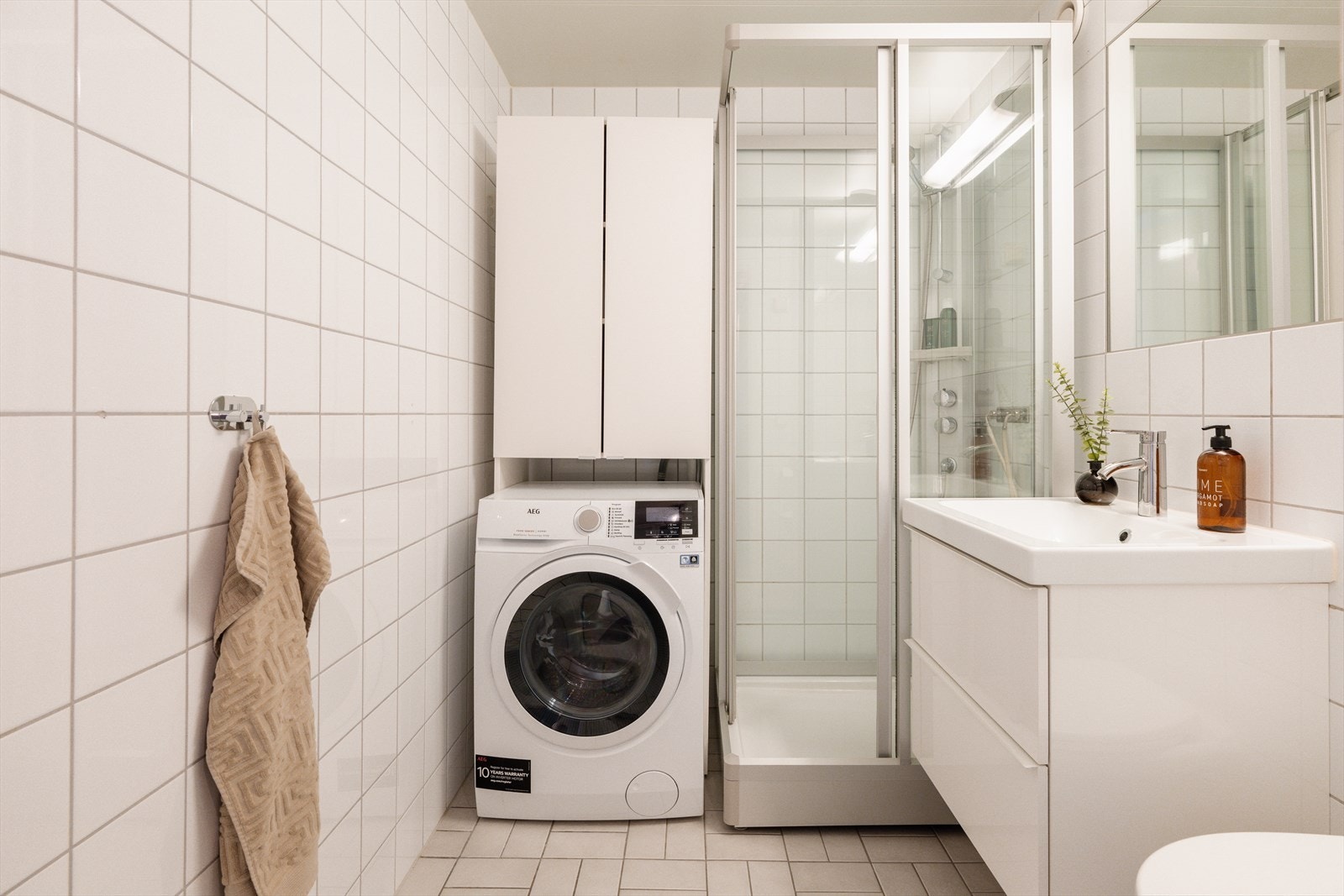 Flislagt baderom med varme i gulvet og praktisk opplegg for vaskemaskin. Galleribilde