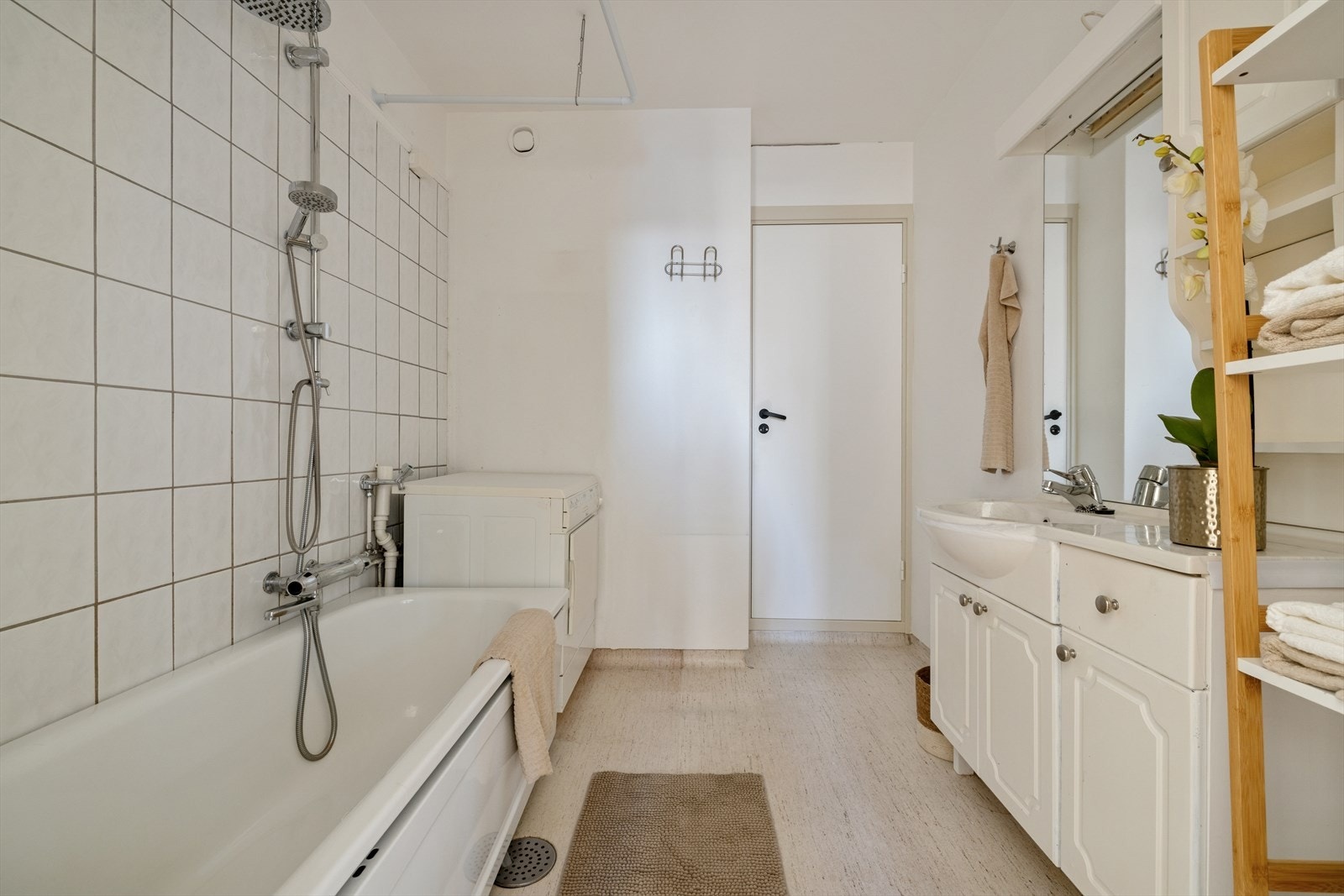 Rommet er innredet med badekar, servant med underskap, speil med overlys, veggskap og har opplegg for vaskemaskin. Galleribilde
