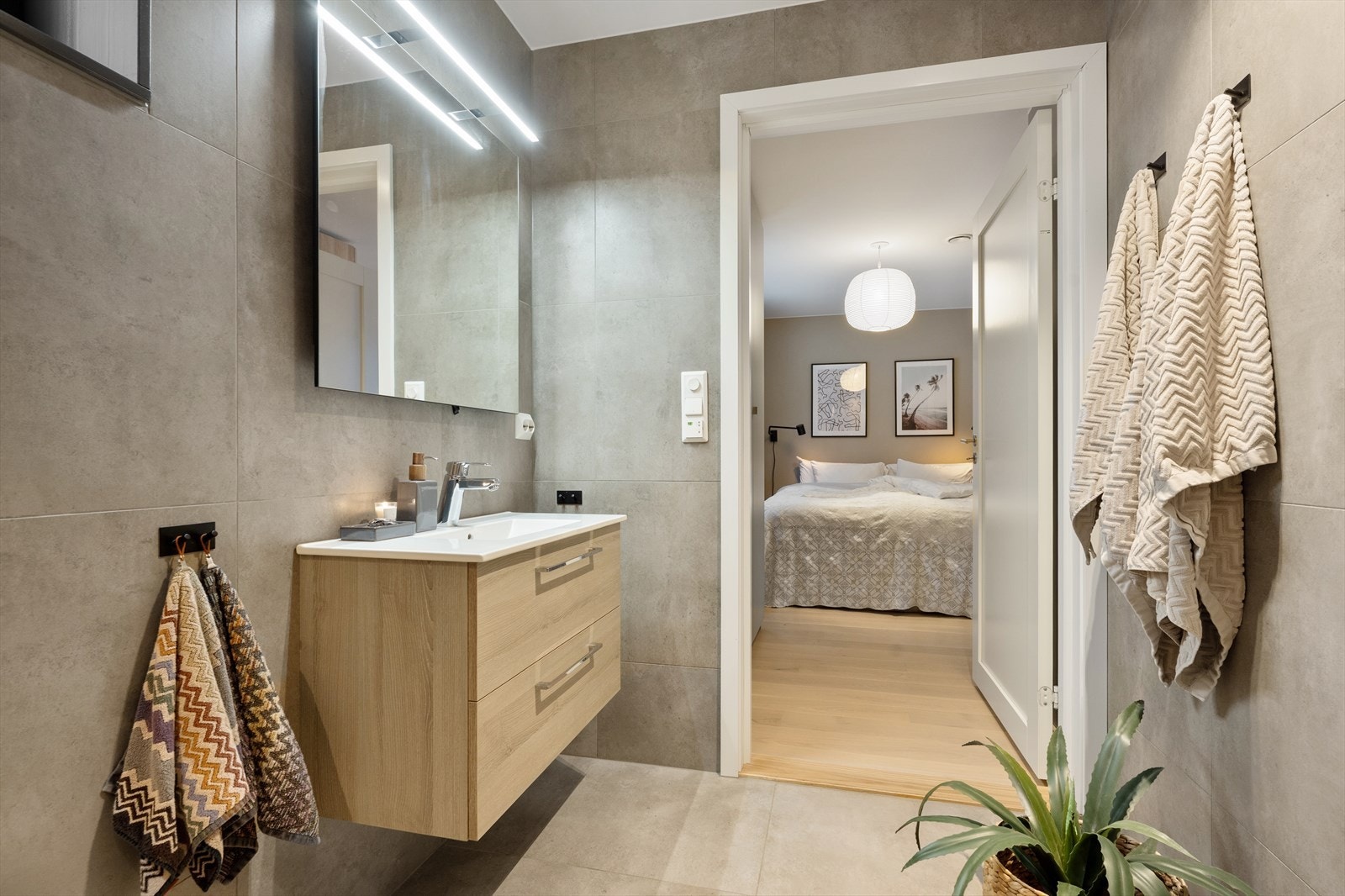 Badet er innredet med servantskap med nedfelt servant, speil med integrert belysning, vegghengt klosett med innebygget sisterne samt en romslig dusjsone med innfelte dusjdører i herdet glass. Det er varmekabler i gulv og downlights i himling. Galleribilde