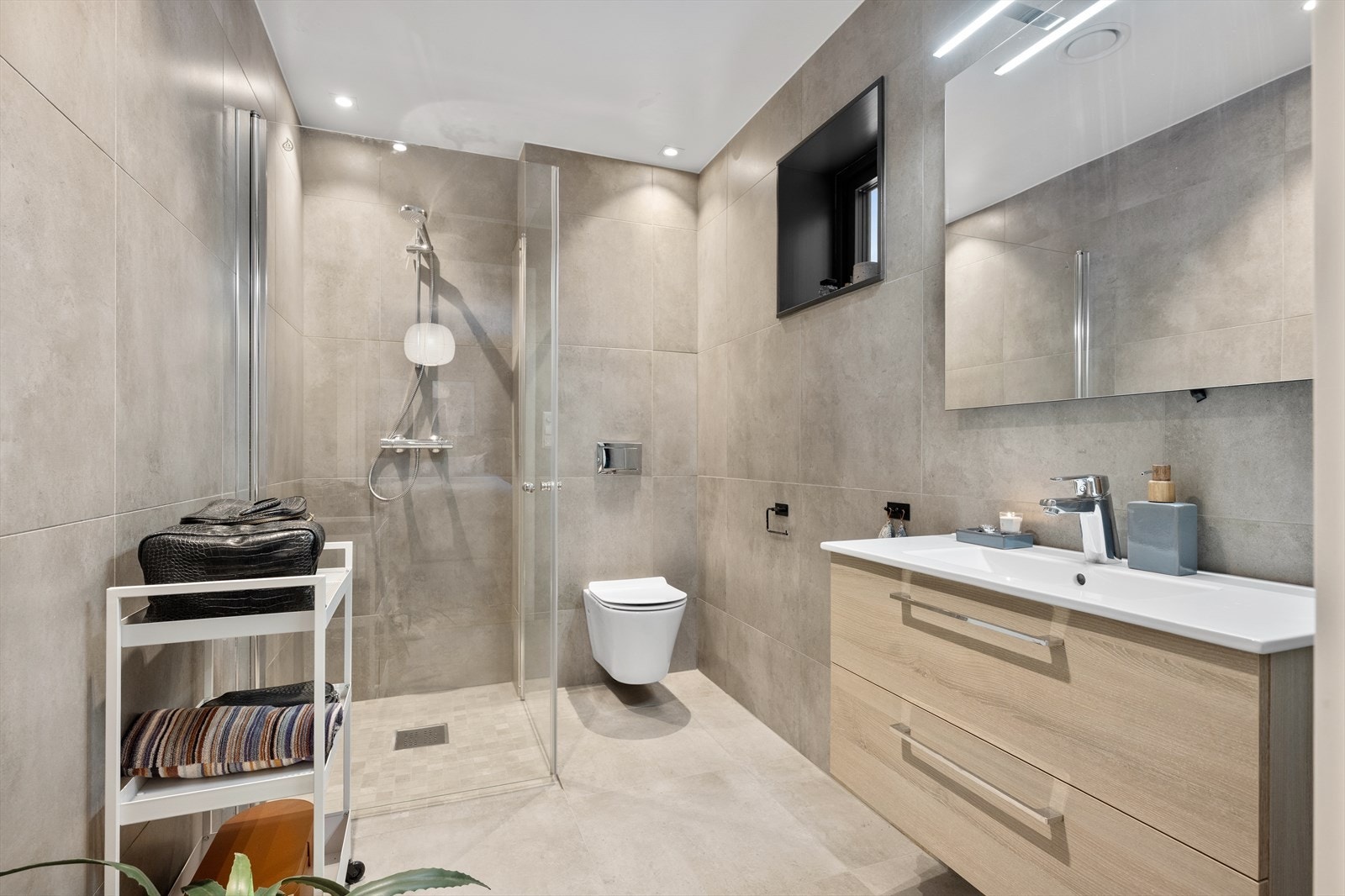 Tilknyttet hovedsoverommet er det et pent bad med flislagt gulv og vegger i tidløse fargetoner. Galleribilde