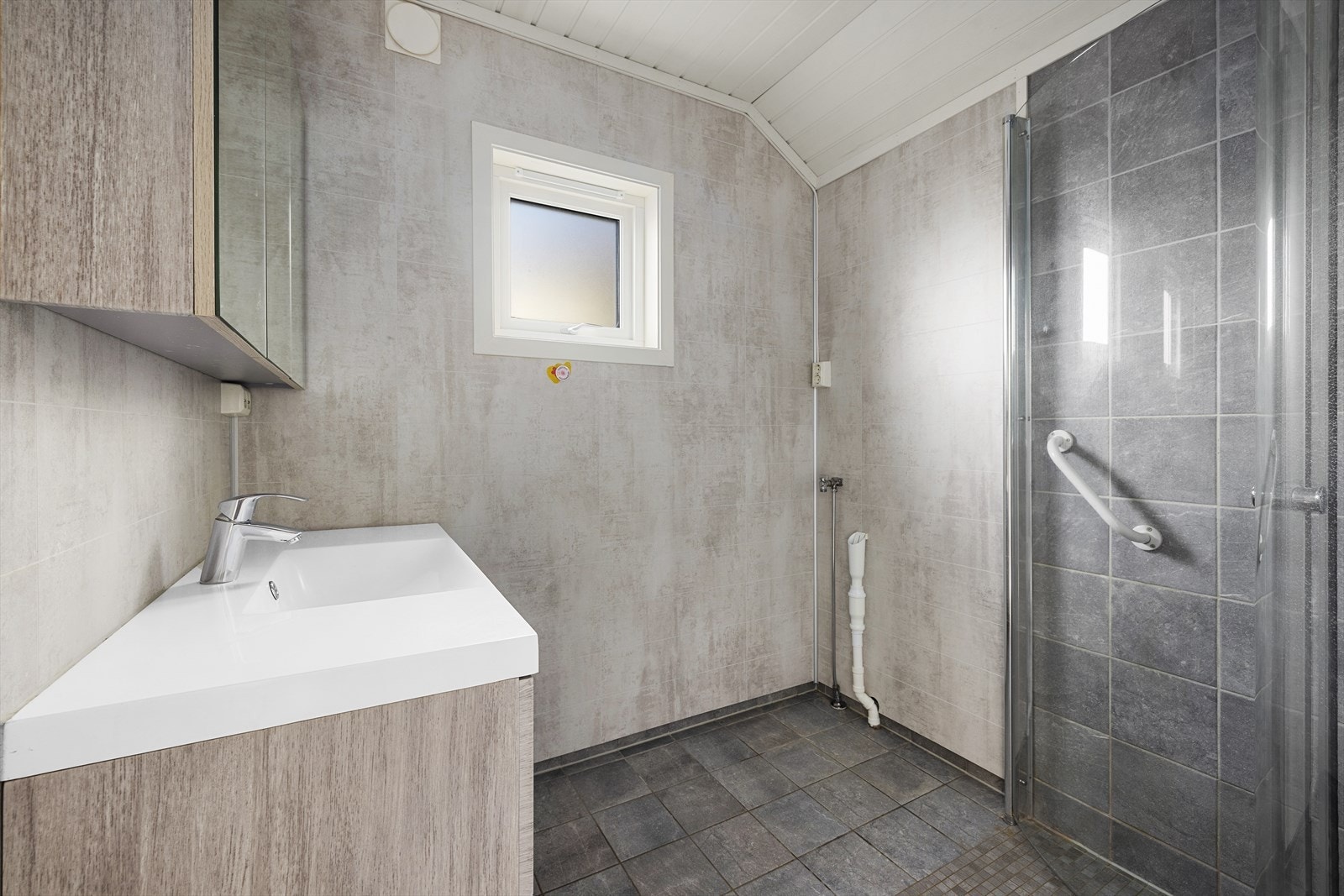 Baderommet er nytt i ca. 2020. Moderne baderomsinnredning, speilskap, dusjhjørne og opplegg for vaskemaskin Galleribilde