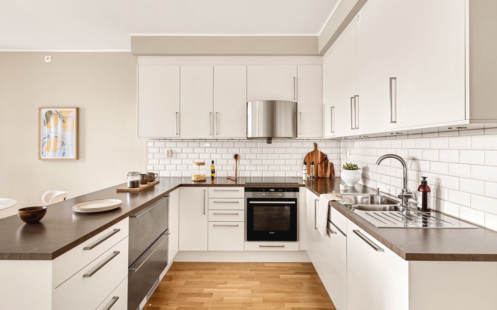 Kjøkkeninnredningen inneholder nedfelt vask, platetopp, komfyrvakt, ventilator, oppvaskmaskin, kjøleskuff og stekeovn Galleribilde