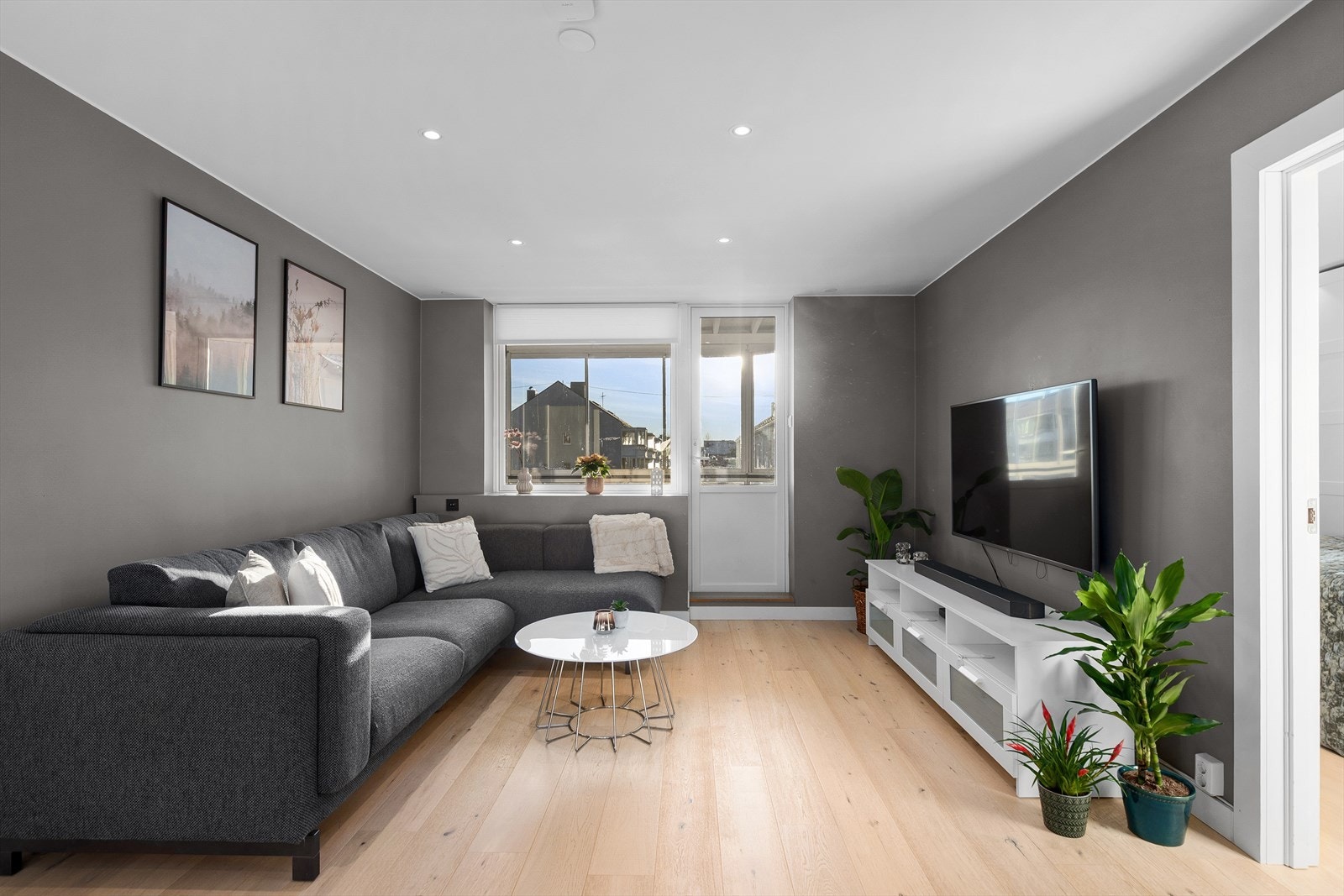 Romslig og innbydende stue med en-stavs eikparkett på gulv og senket himling med downlights. Galleribilde