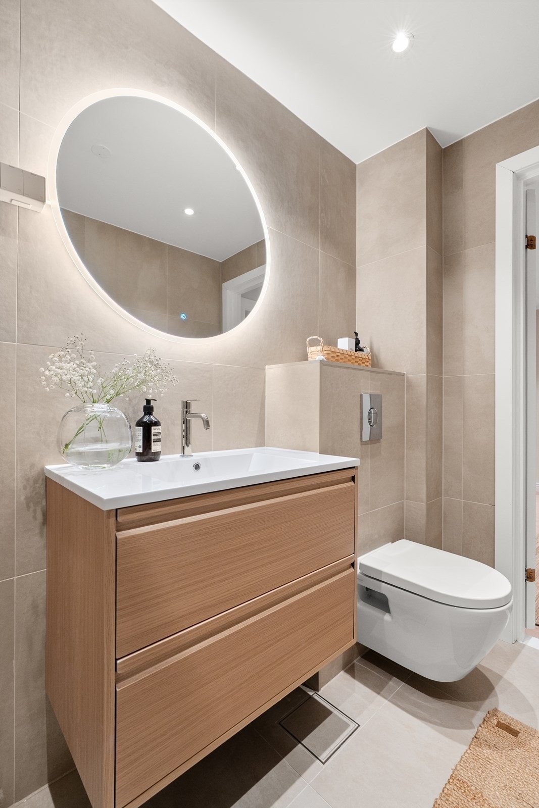 Badet er innredet med vegghengt klosett, servant med innredning, speil med integrert belysning og dusjhjørne med glassvegger. Galleribilde