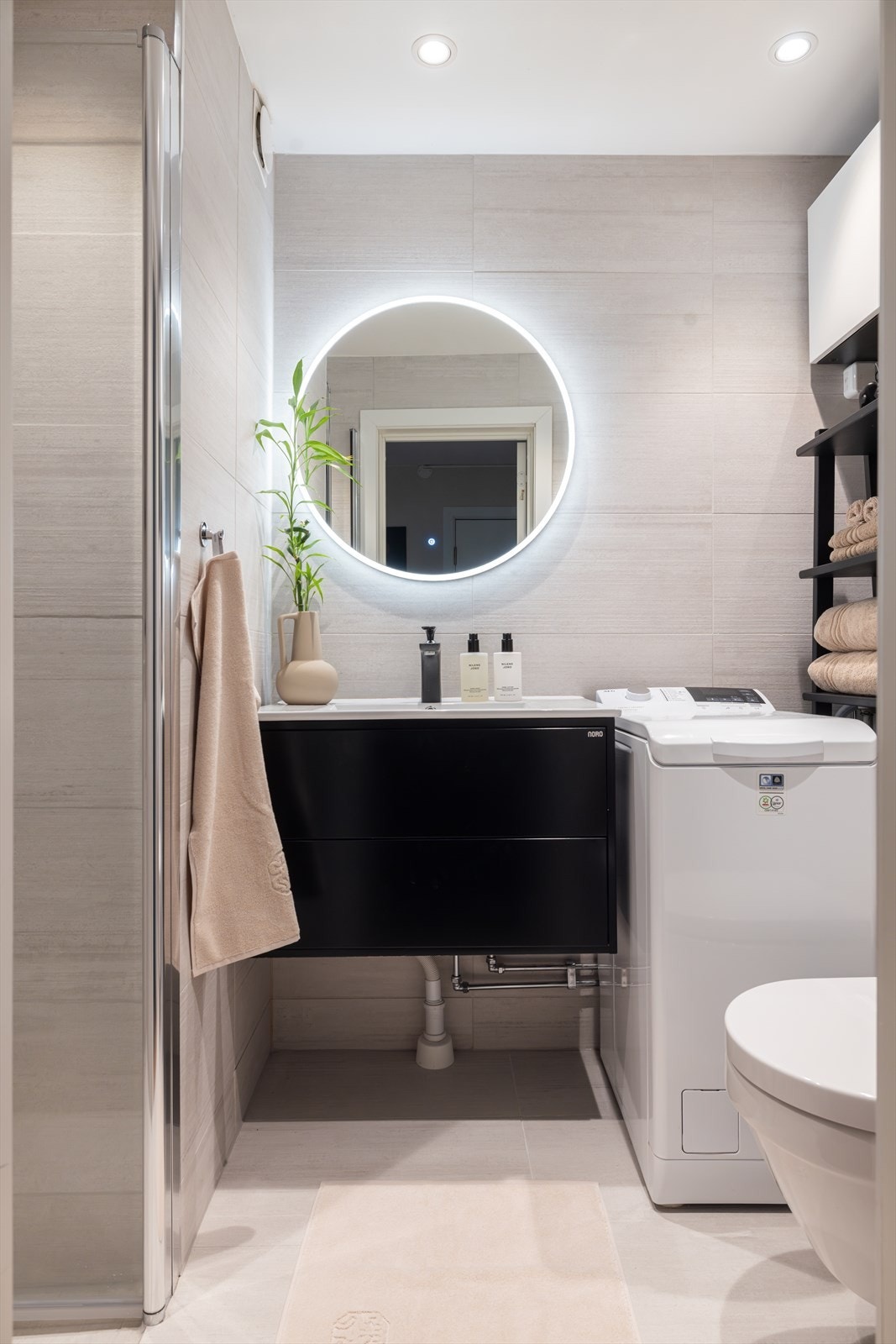 Badet er innredet med en lekker heldekkende servant på underskap, rundt speil med integrert belysning og stemningsfulle downlights i taket. Galleribilde