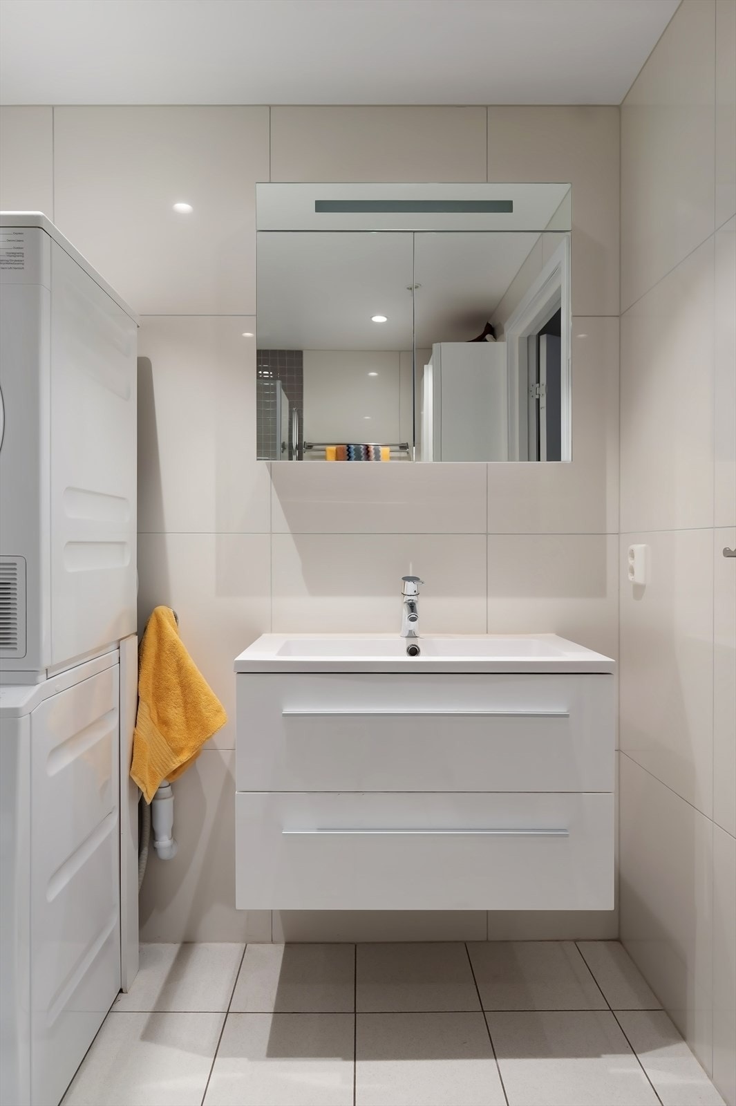 Baderomsinnredning med nedfelt servant, veggmontert toalett og dusjhjørne. Opplegg for vaskemaskin og tørketrommel i søyle. Galleribilde