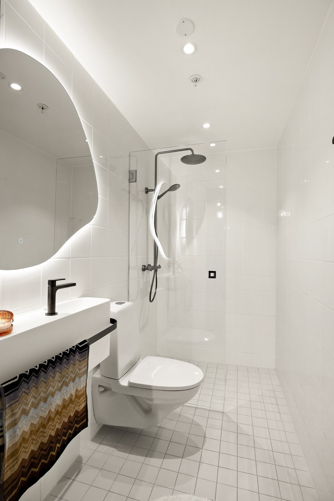 Badet er utstyrt med toalett og dusjløsning med innfellbare glassdører. Overflatene gir et tidløst og moderne preg. Galleribilde