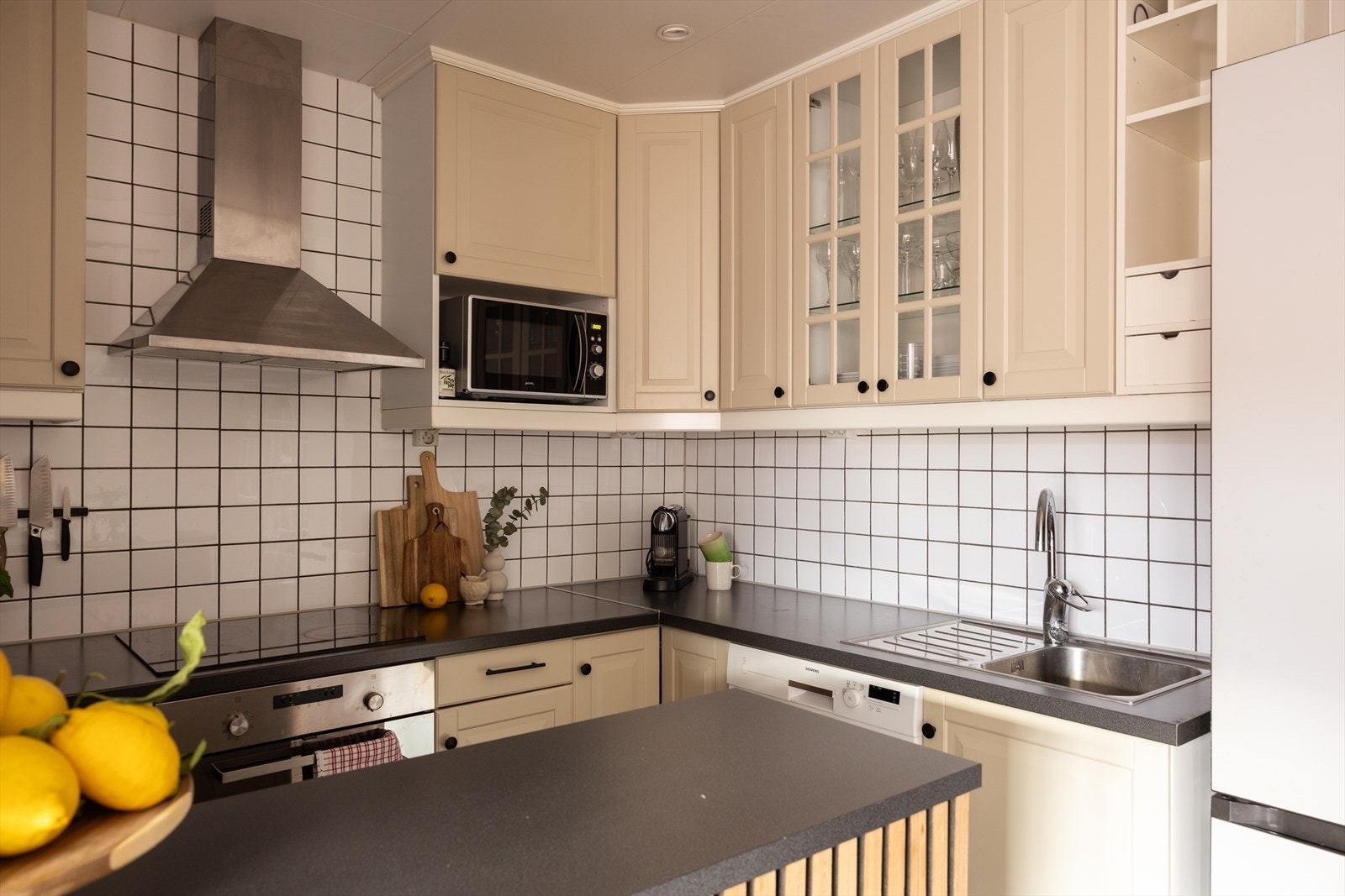 Tidløst kjøkken fra IKEA med laminat benkeplate, integrert platetopp, stekeovn, oppvaskmaskin i nisje og frittstående kombiskap kjøpt nytt i 2024 Galleribilde
