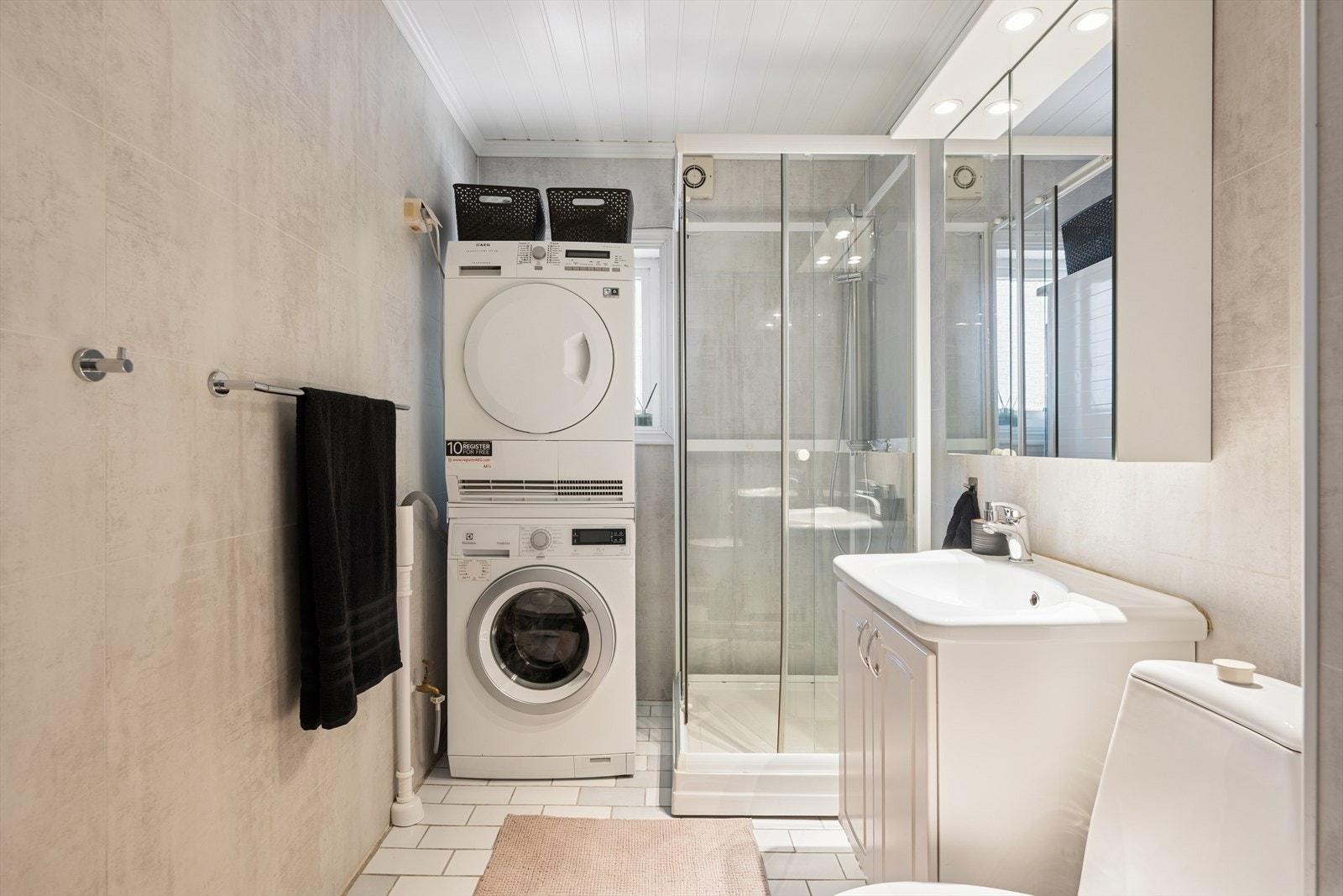 Badet har innredning med nedfelt servant, toalett, dusjkabinett og opplegg for vaskemaskin Galleribilde