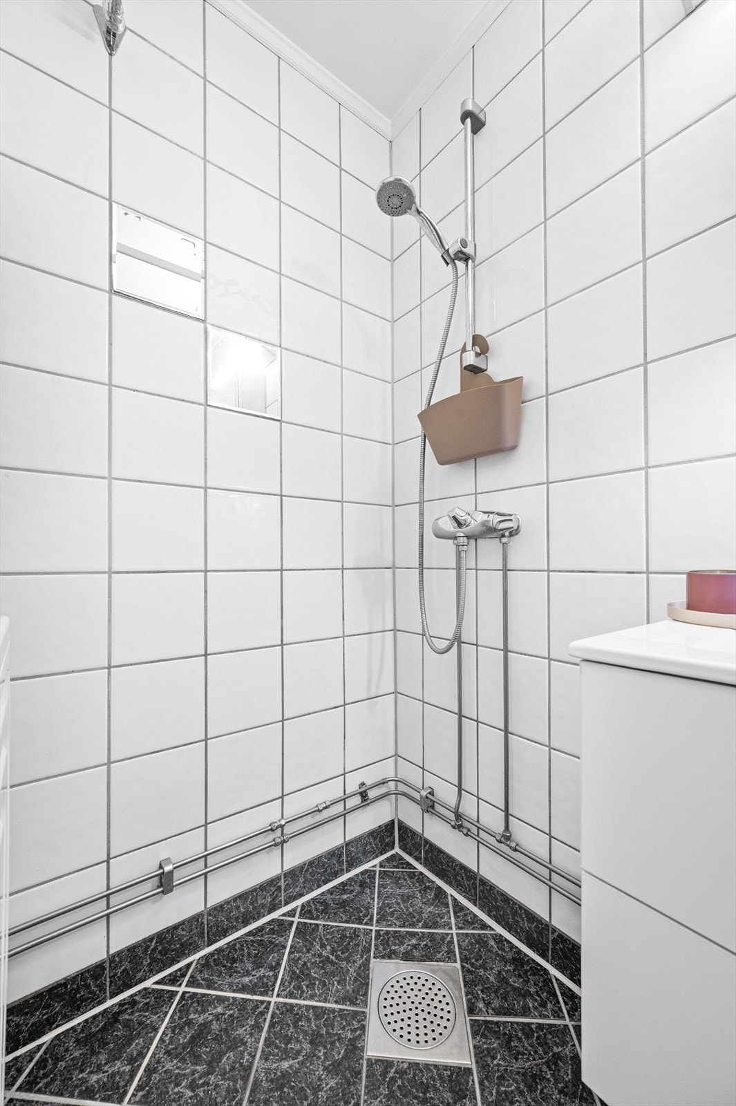 Badet består av toalett, dusj på vegg, vask og opplegg til vaskemaskin. Galleribilde