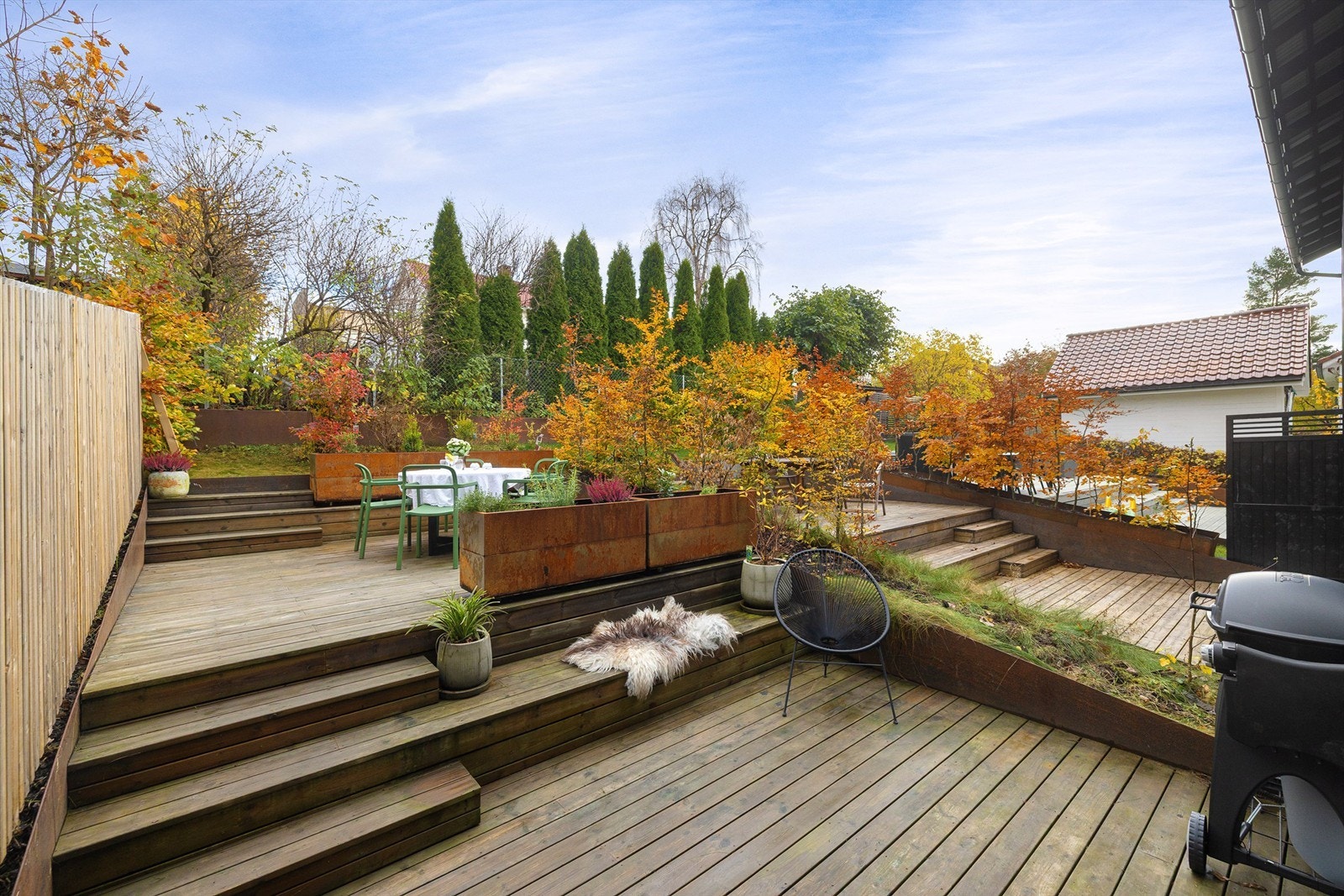 Bakhagen til huset er fordelt over flere nivåer med fine terrasser og blomsterkasser i cortenstål Galleribilde