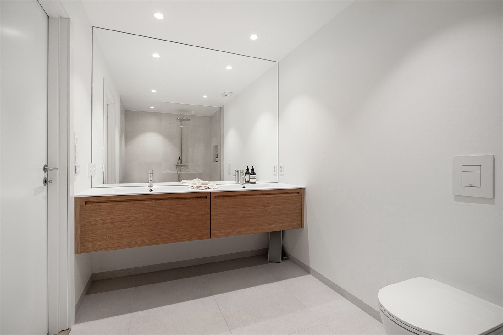 Lekkert bad i underetasjen, med delikate fliser på gulv/malte flater. Plassbygget innredning med servanter og skuffer fra Elen Møbelstudio Galleribilde