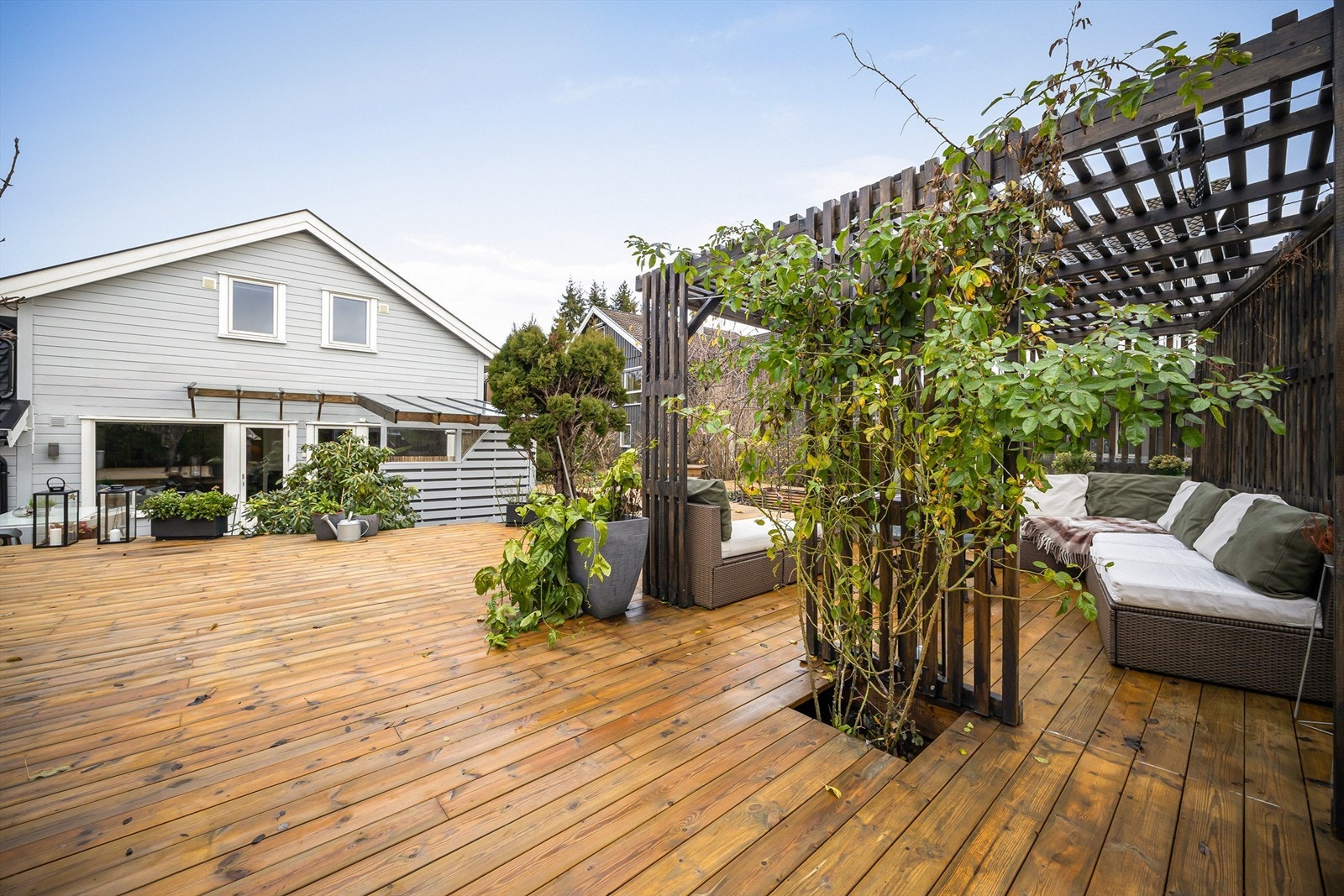 Plattingen/terrassen er opparbeidet i flere nivåer med nedfelte bed og strekker seg rundt to sider av boligen Galleribilde