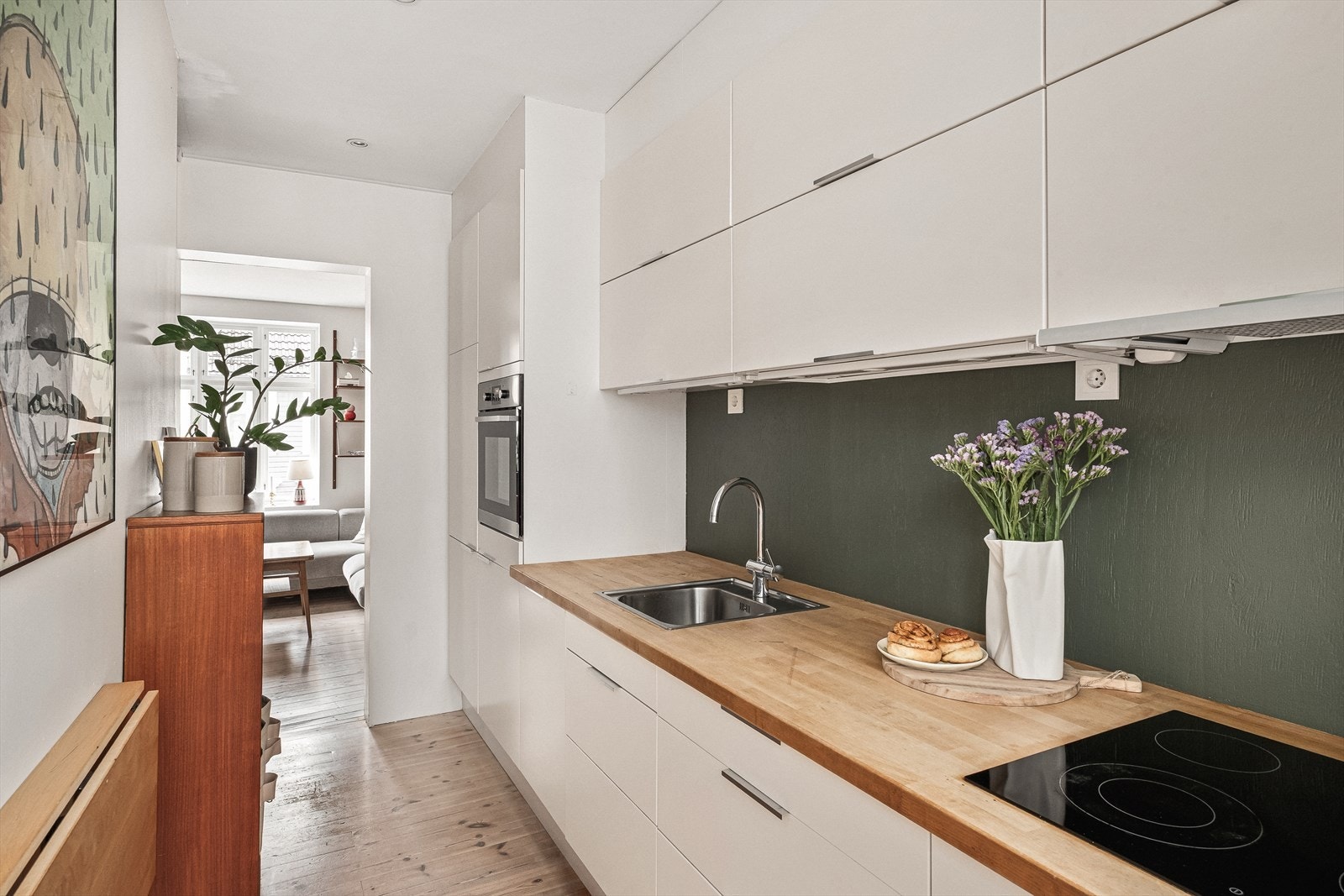 Kjøkkeninnredning fra Ikea med hvite glatte fronter og laminat benkeplate med nedfelt vask. Ventilator med mekanisk avtrekk. Galleribilde