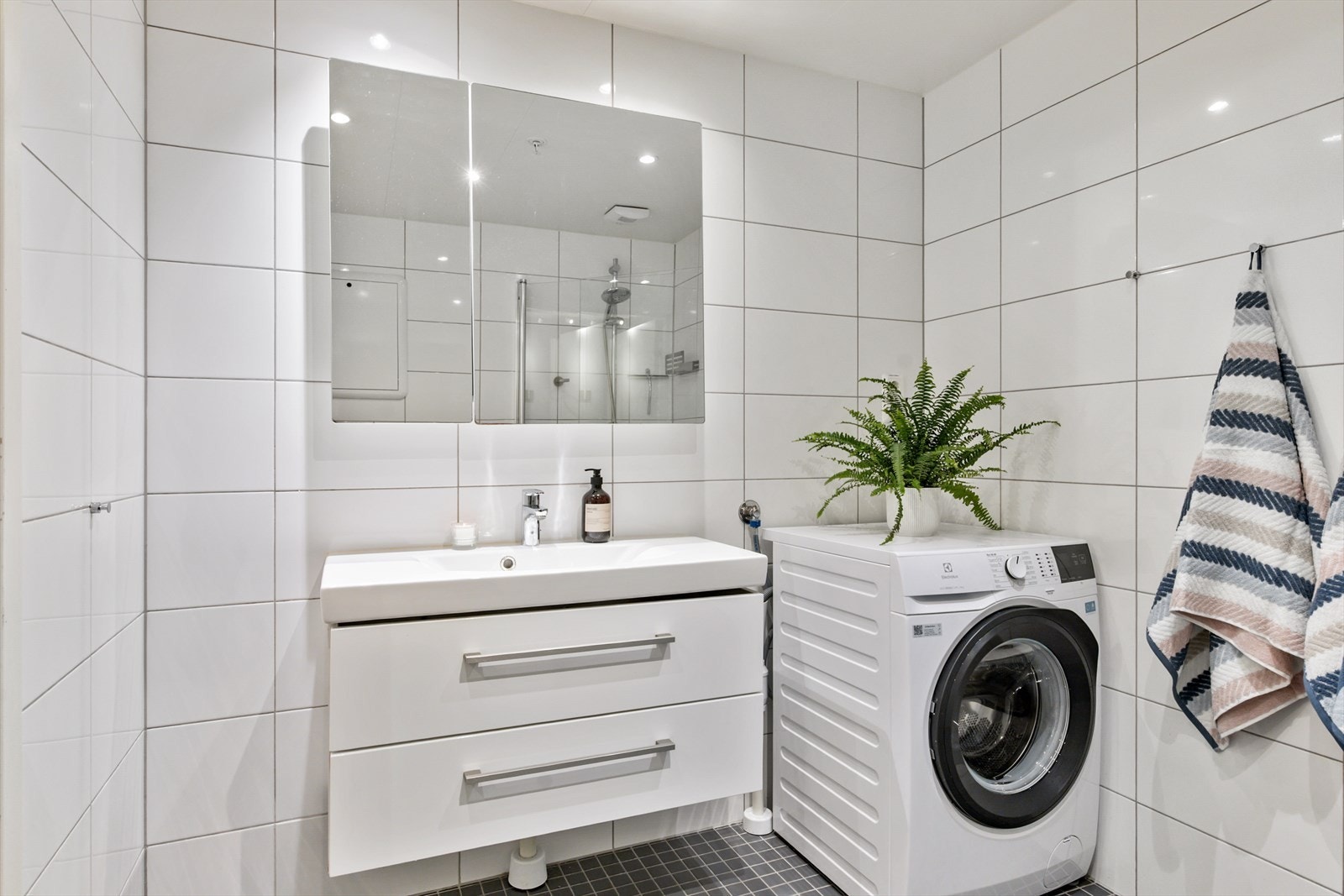 Badet består av servantskap med nedfelt servant, veggskap med speildører, vegghengt klosett og dusjsone med innfelte dusjdører i herdet glass. Galleribilde